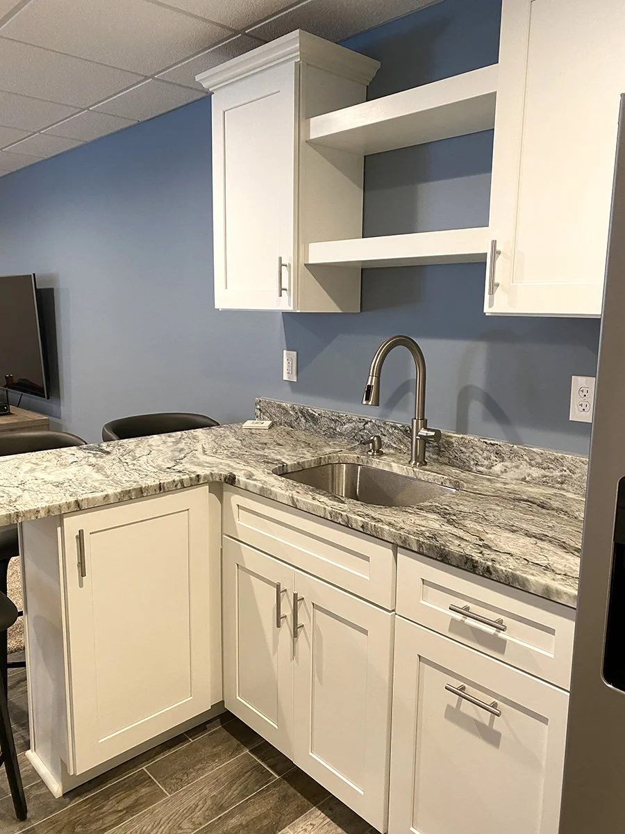 Kitchen with white cabinets, granite countertop, stainless steel sink, and blue wall.
