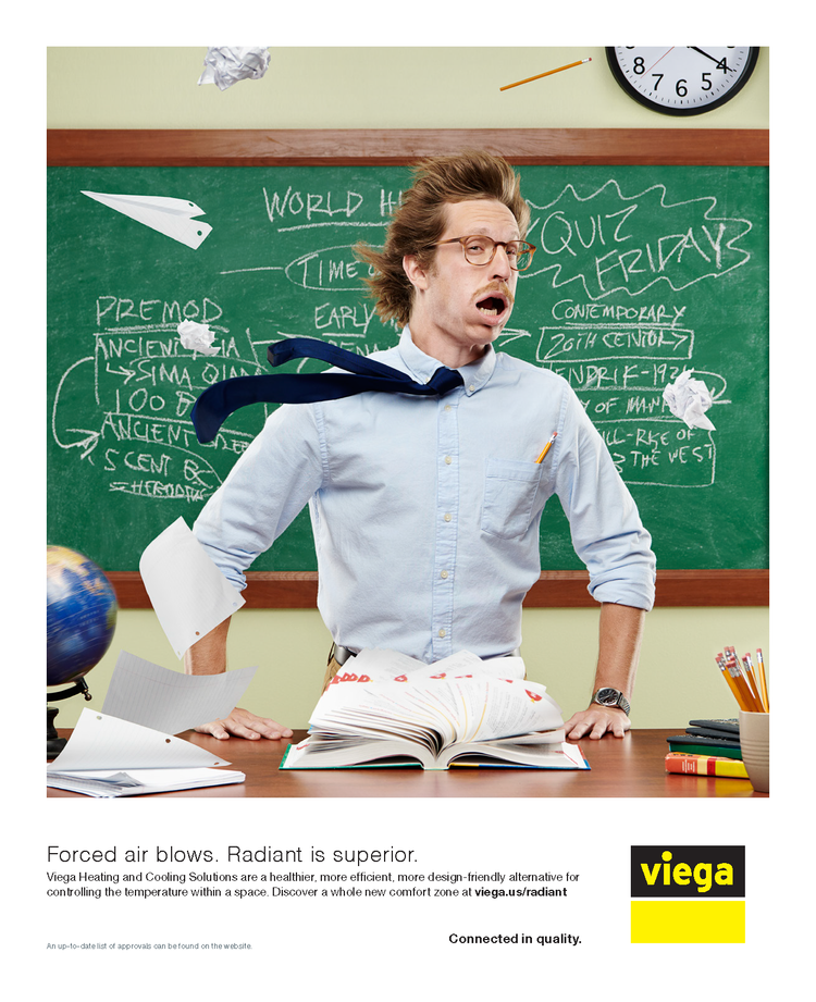 A frustrated teacher with messy hair and glasses stands at a desk with papers and an open book in a classroom with a green chalkboard covered in handwritten notes and a clock on the wall.