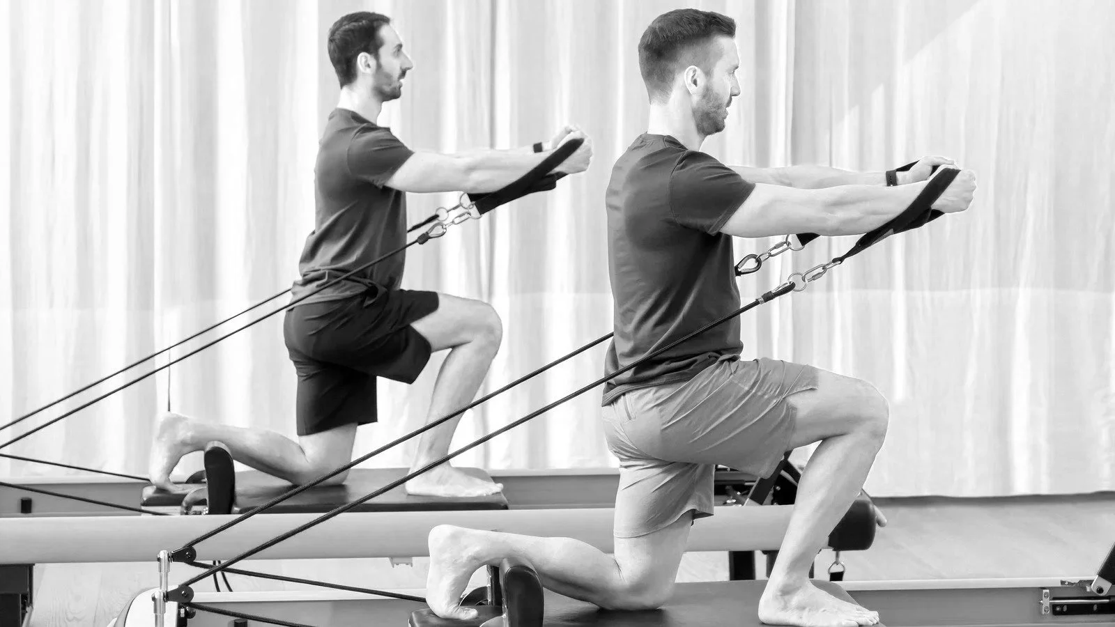 Black and white image of men doing Reformer Pilates