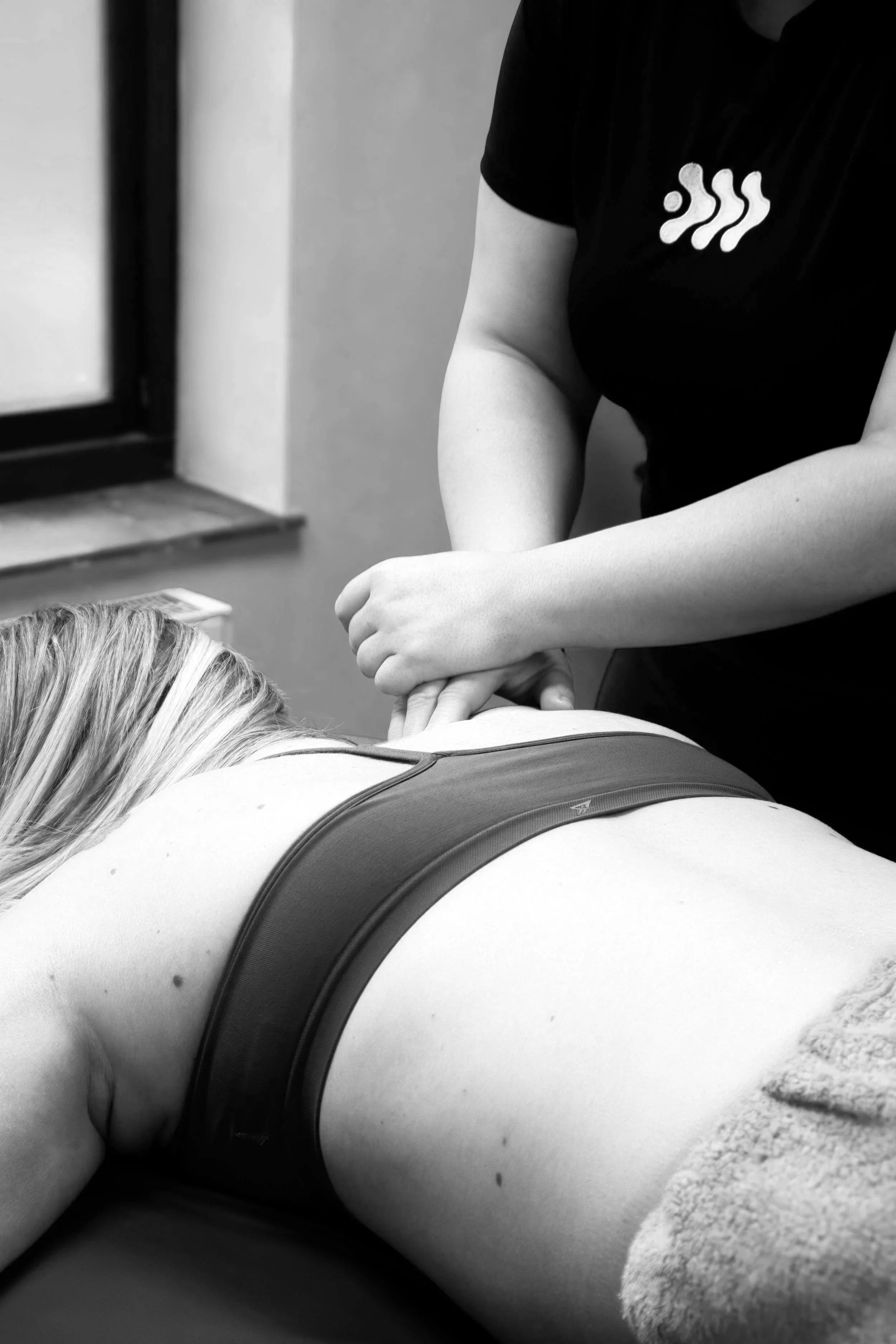 Black and white photo of a practitioner at Apollo Health Collective using Osteopathy to treat a female client's low back pain