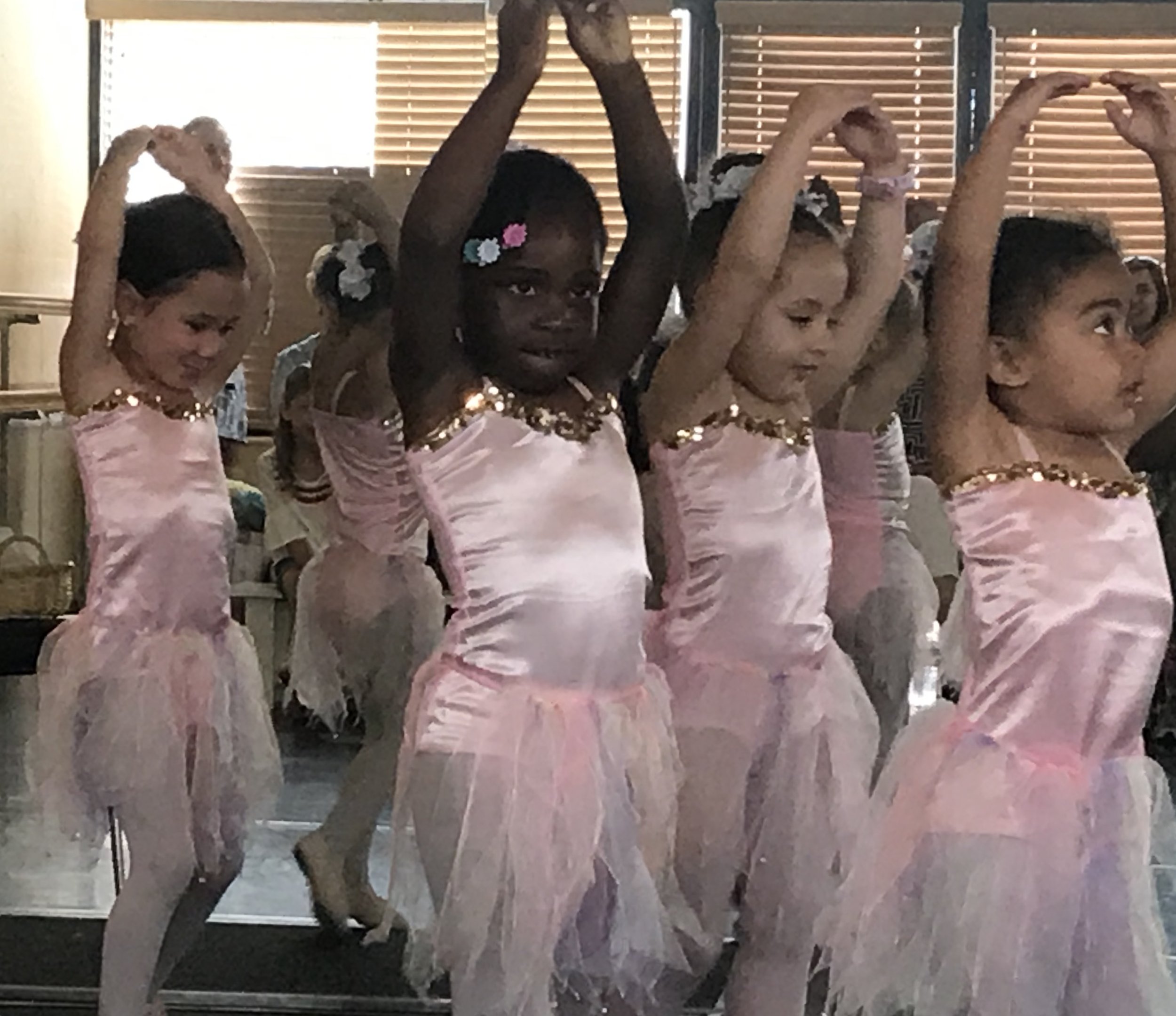 A group of young girls in pink ballet costumes practicing ballet dance in a studio.