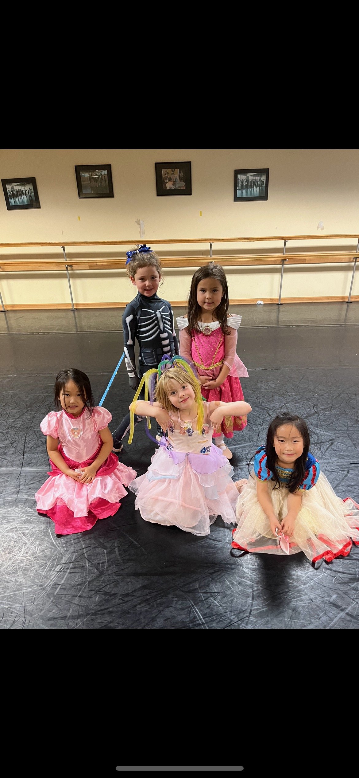 Girls in colorful costumes posing in a dance studio.