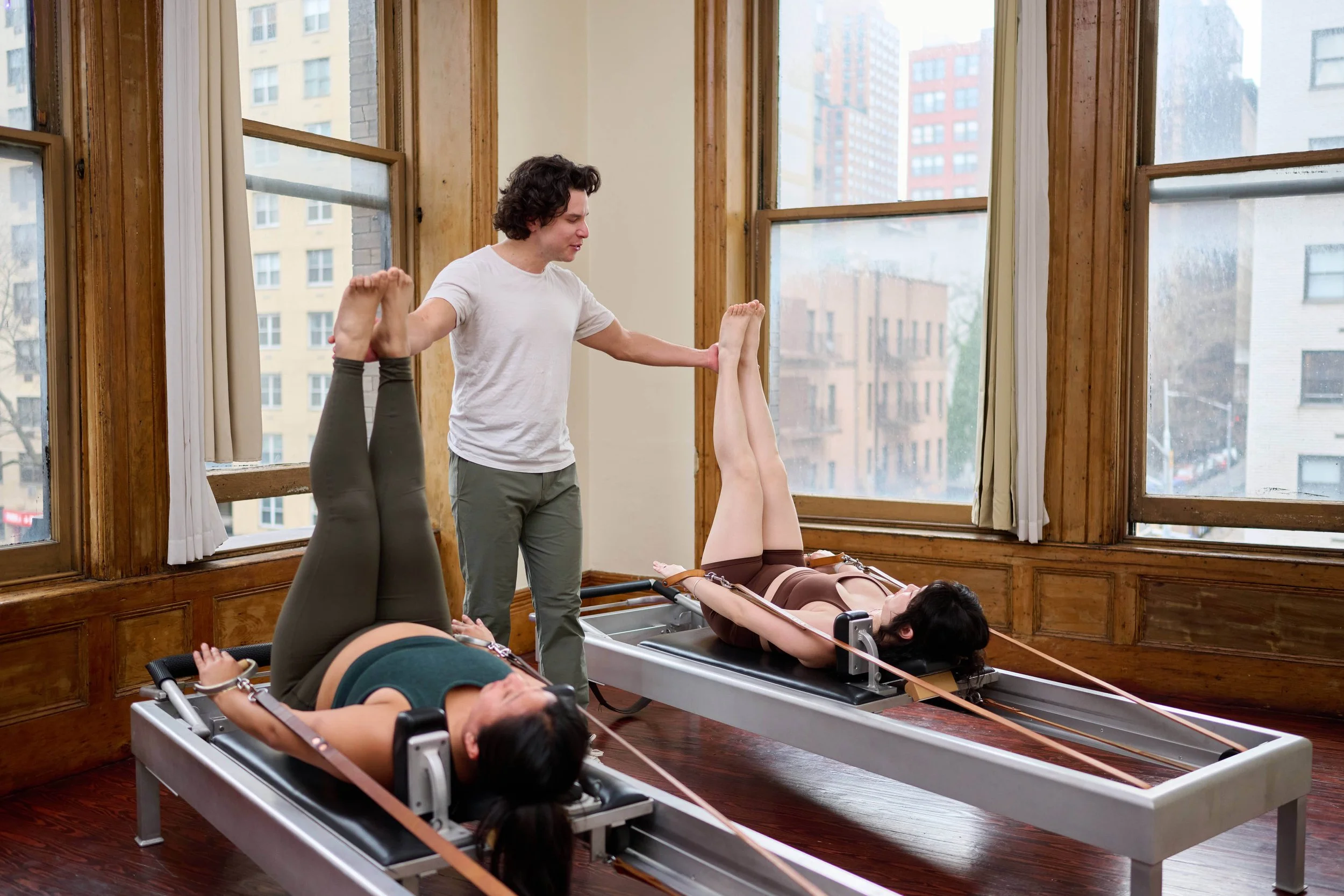 Cam teaching a duet with two students on reformers