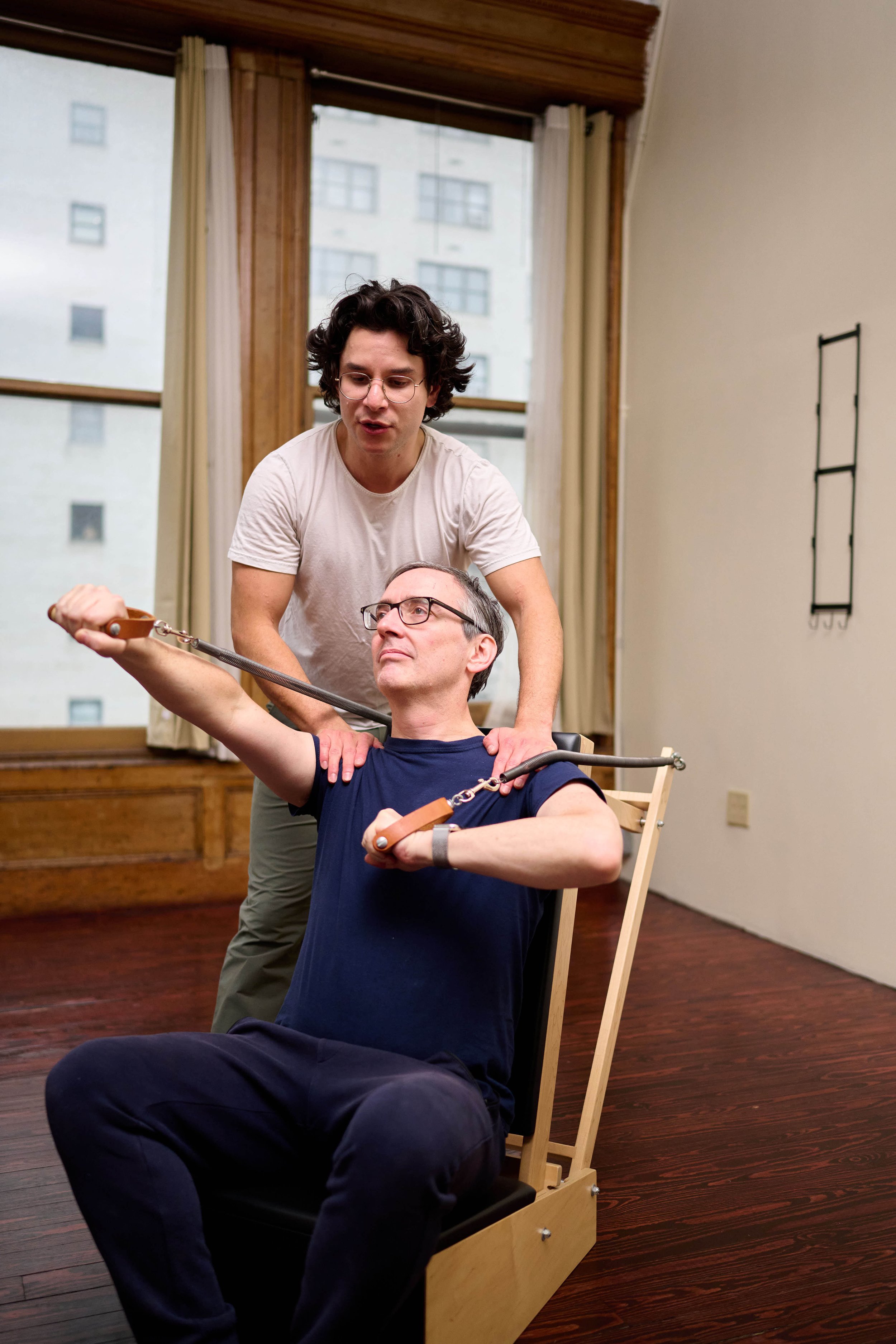 Cam teaching a private Pilates session with student on a Pilates baby chair