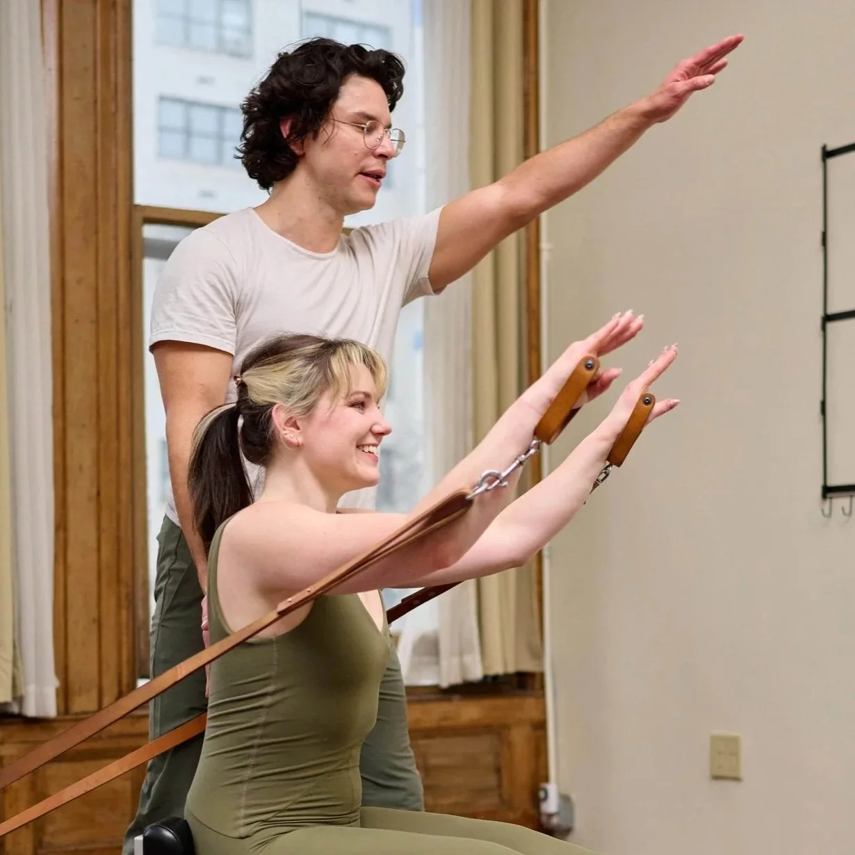 Cam teaching Pilates student on the reformer