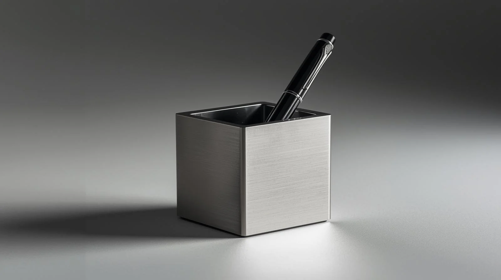 Un stylo-plume noir dans un porte-stylo en métal argenté, posé sur une surface plane.
