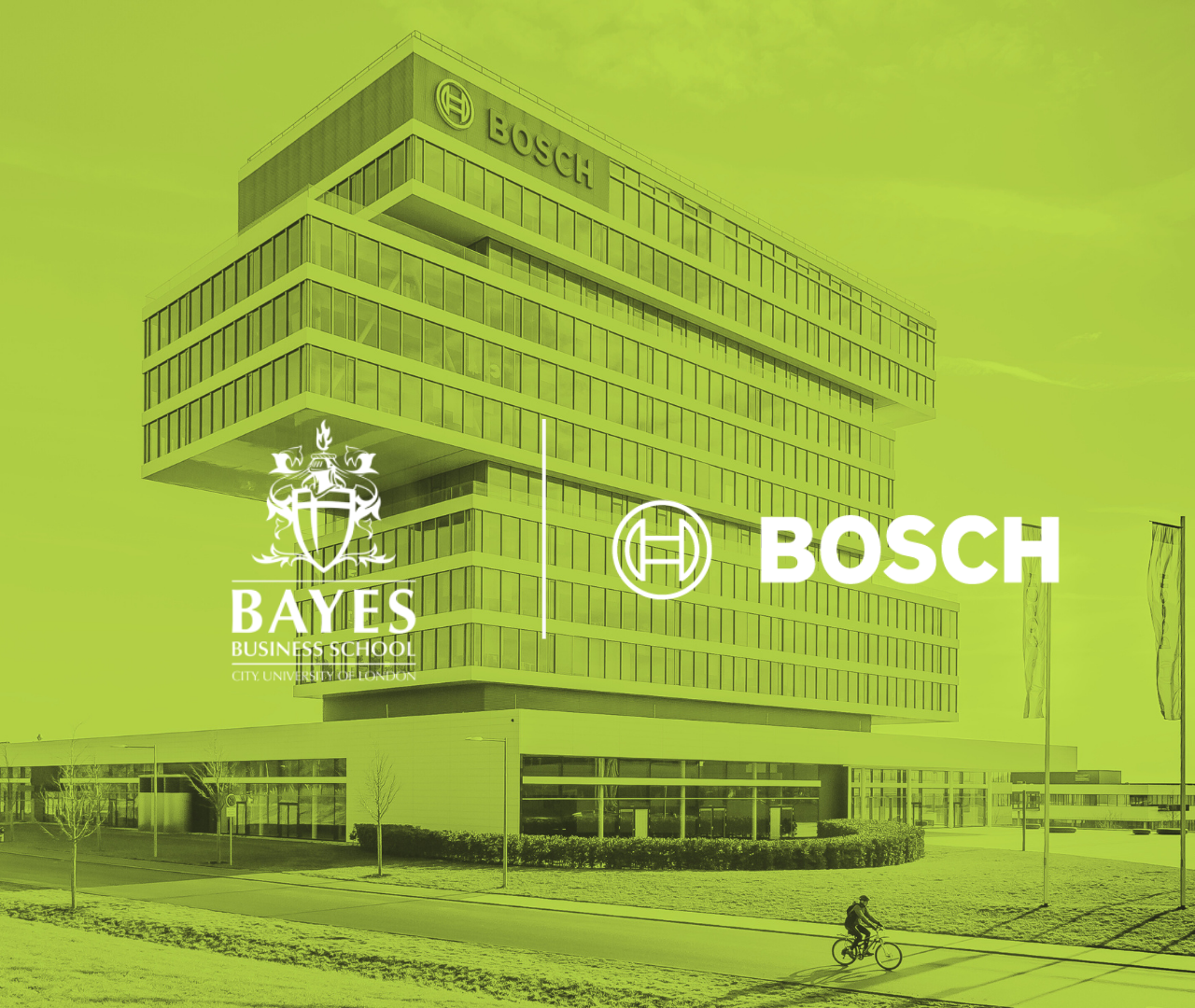 Modern multi-story office building with Bosch logo, and logos for Bayes Business School and City, University of London, displayed on the front. A person is riding a bicycle on the cycle path in the foreground, and a flagpole with flags is visible to the right.