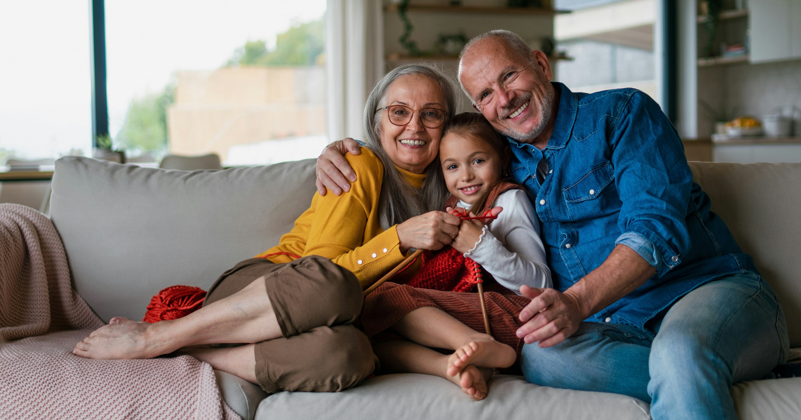 A happy multigenerational family sitting on a sofa, smiling and enjoying time together in a cozy living room.