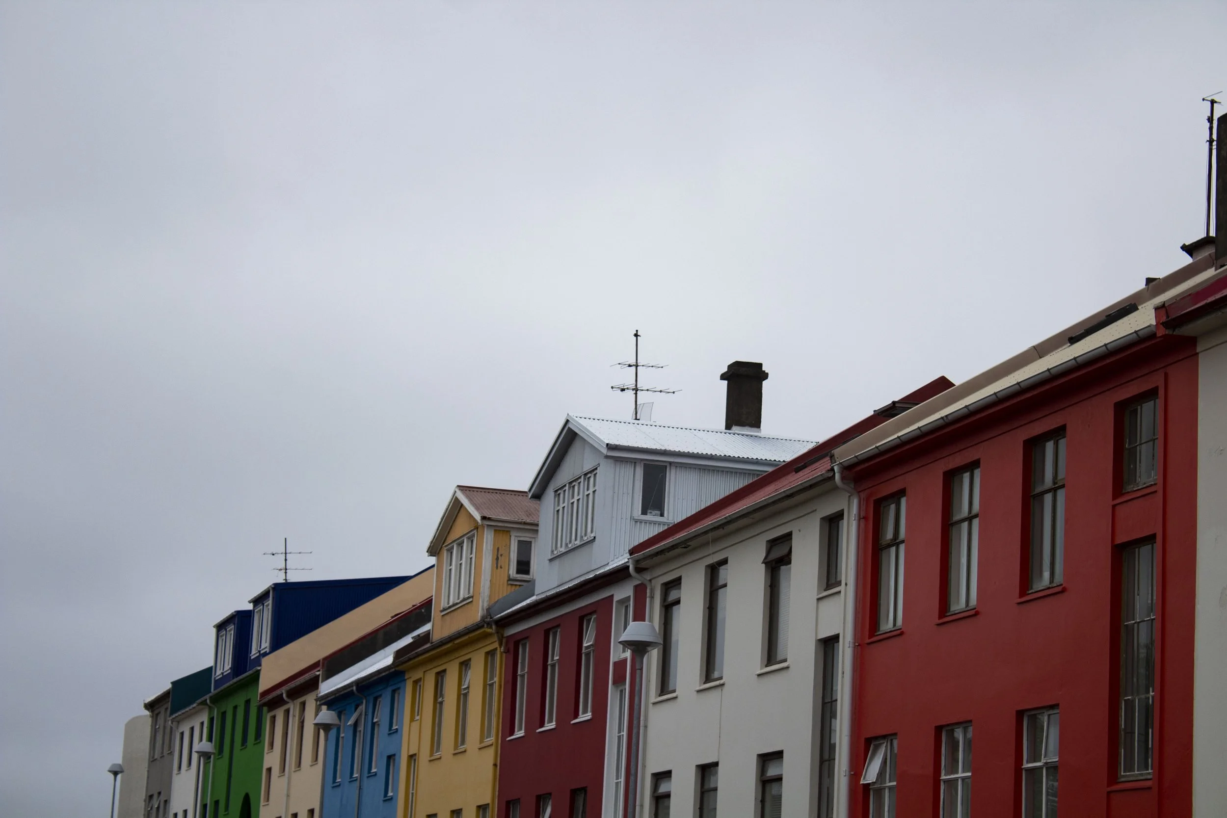 Colorful urban buildings with multiple stories and various window styles under an overcast sky in Reykjavik, Iceland. Taken by Allison Berryman in 2018.