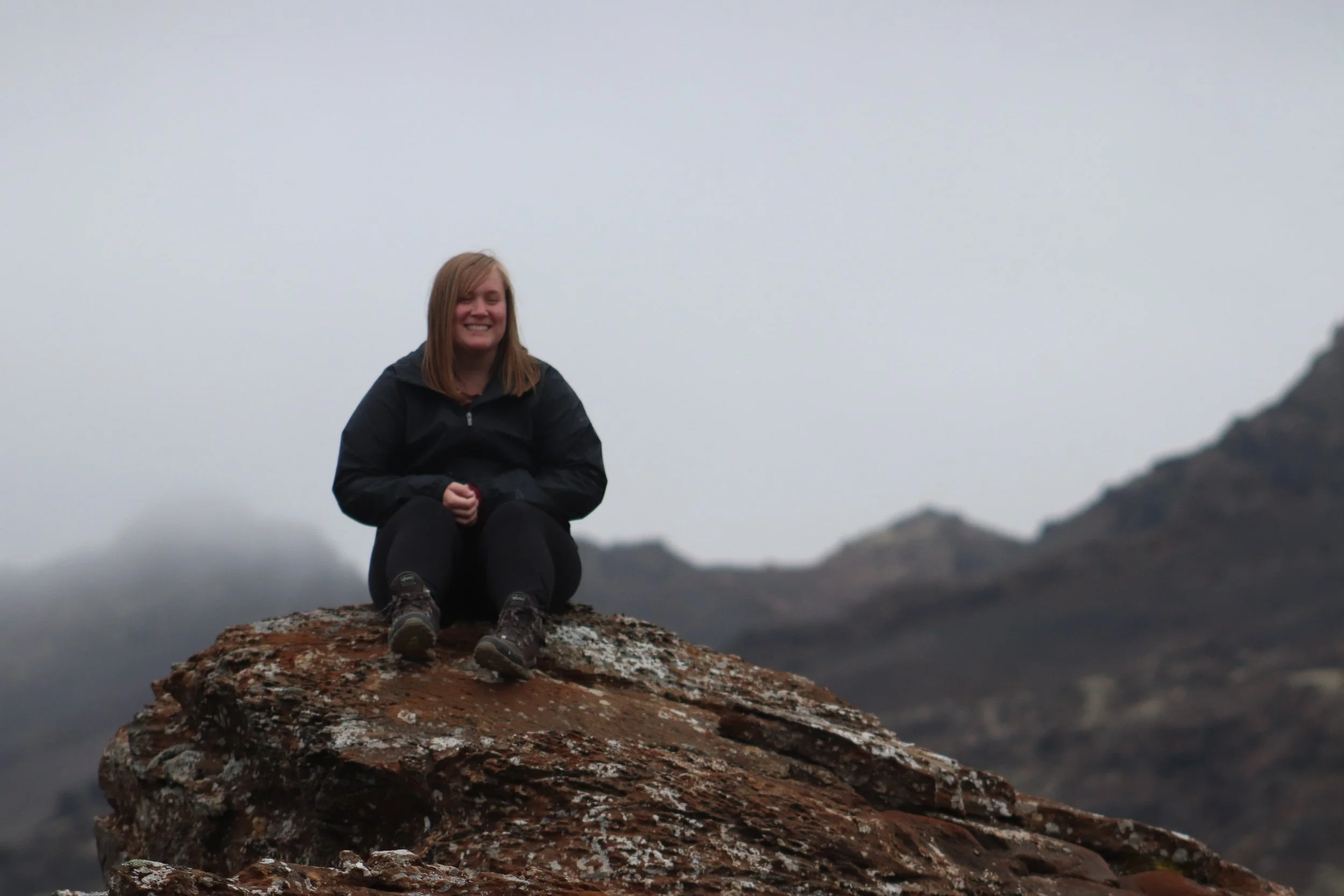 Allison Berryman sitting on top of a high rock in Iceland.