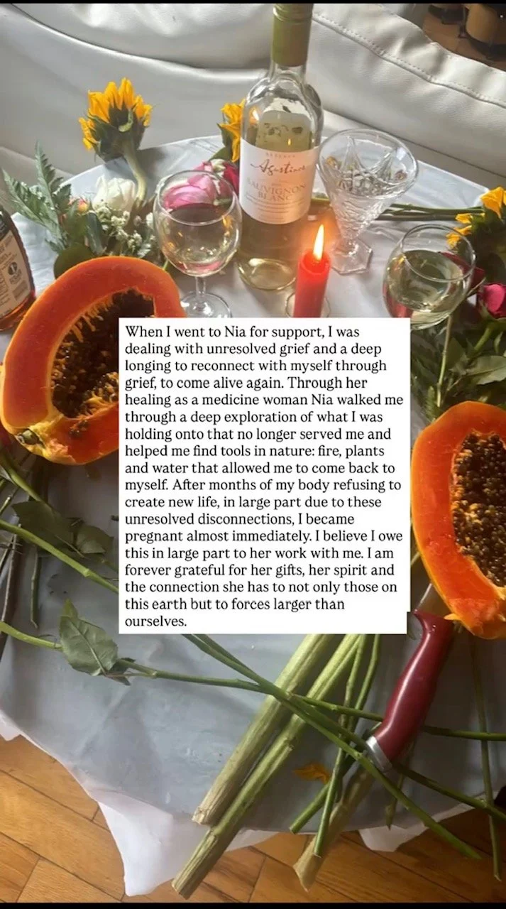 A table decorated with flowers, candles, wine, and two halves of papaya and a note card with a message about healing and gratitude.