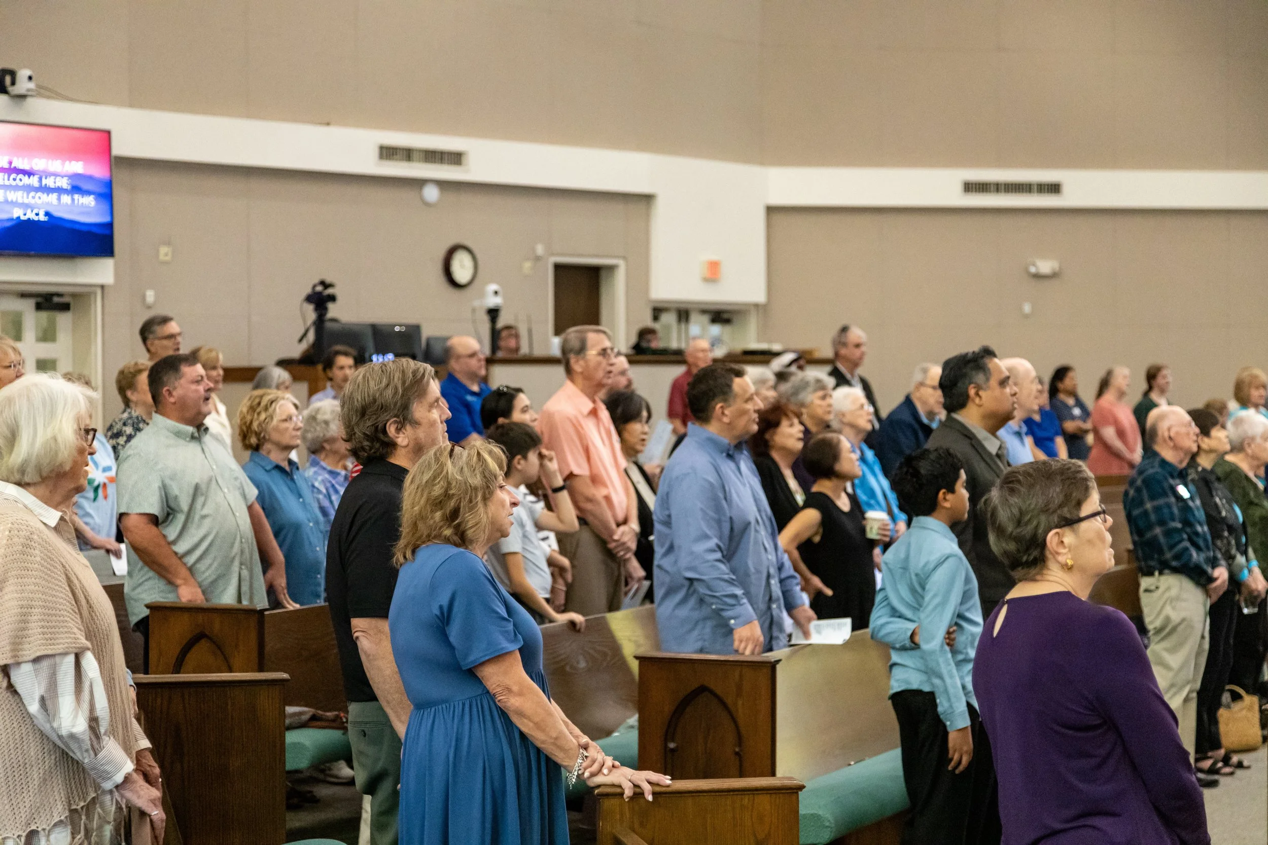 A diverse congregation of people standing in pews, attending a religious service or event inside a church.