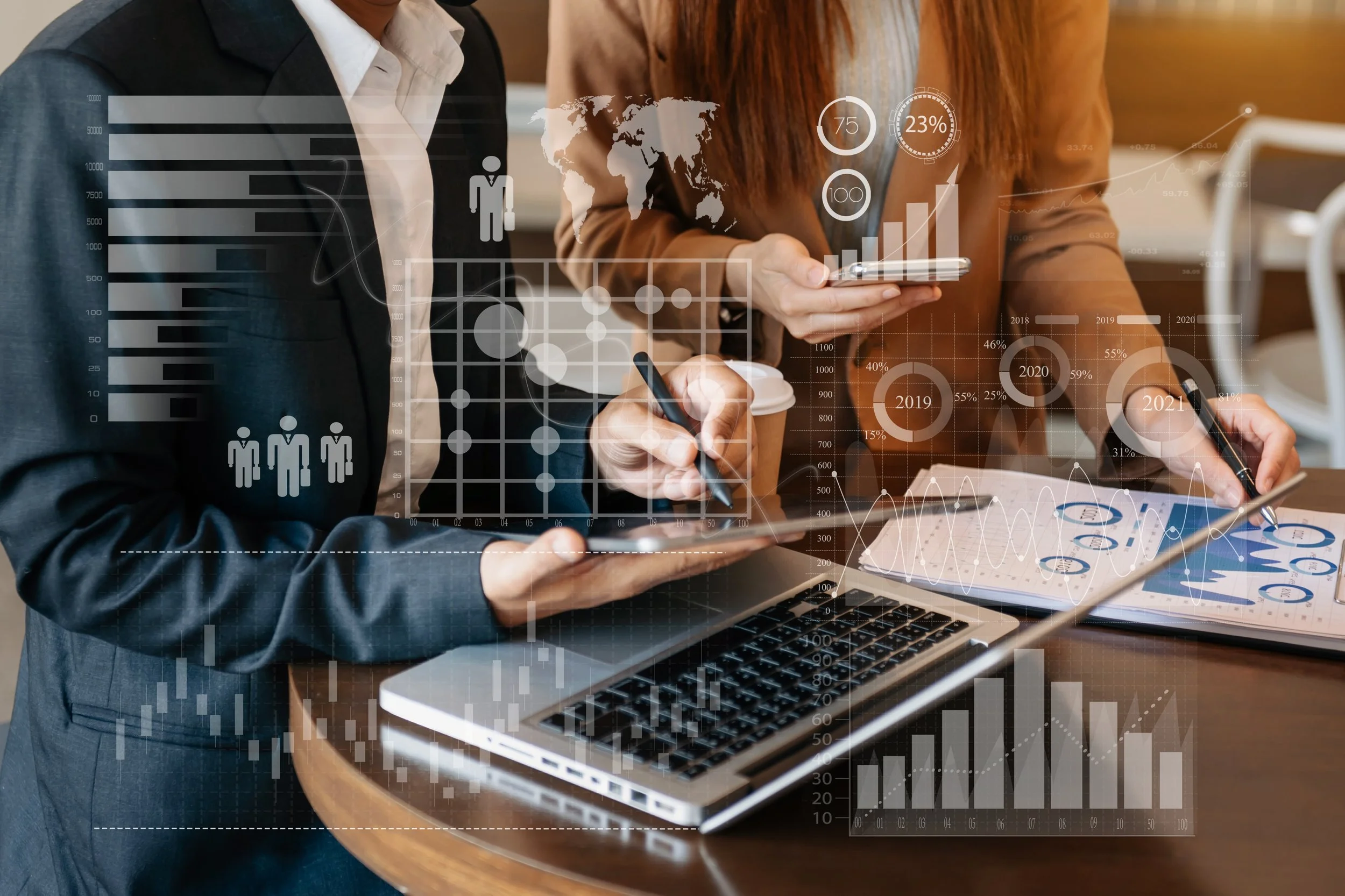 Business professionals analyzing data with charts, graphs, and maps on transparent digital overlay, working on laptops and tablets.