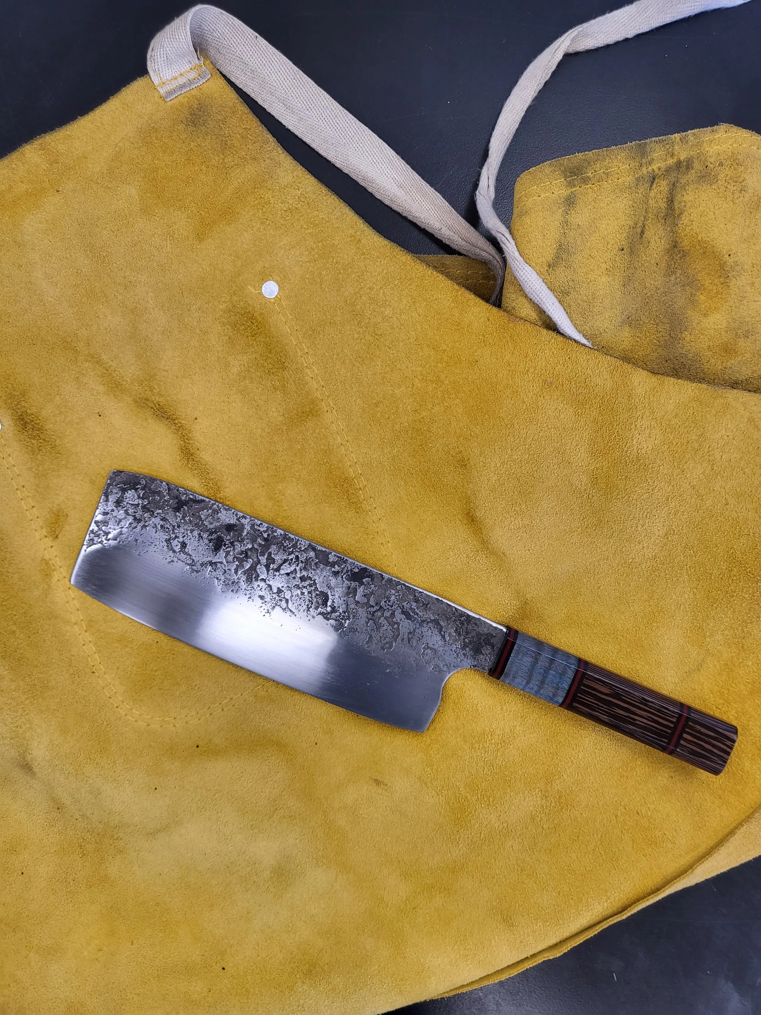A Japanese-style kitchen knife with a patterned wooden handle resting on a yellow cutting board.