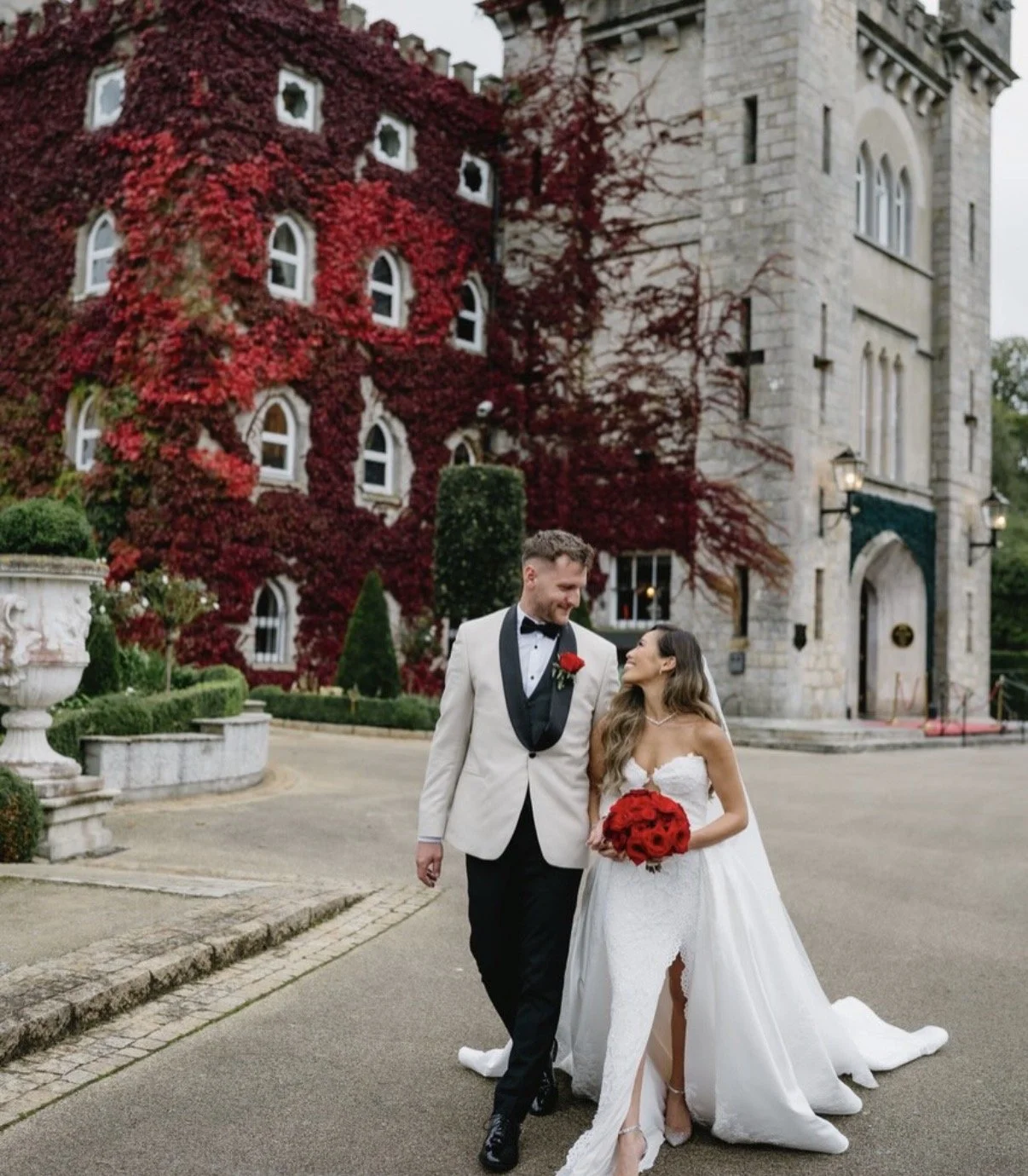 Bride looking at groom lovingly holding trending red rose bouquet by Willow Heather Flowers Cabra Castle County Cavan Ireland.