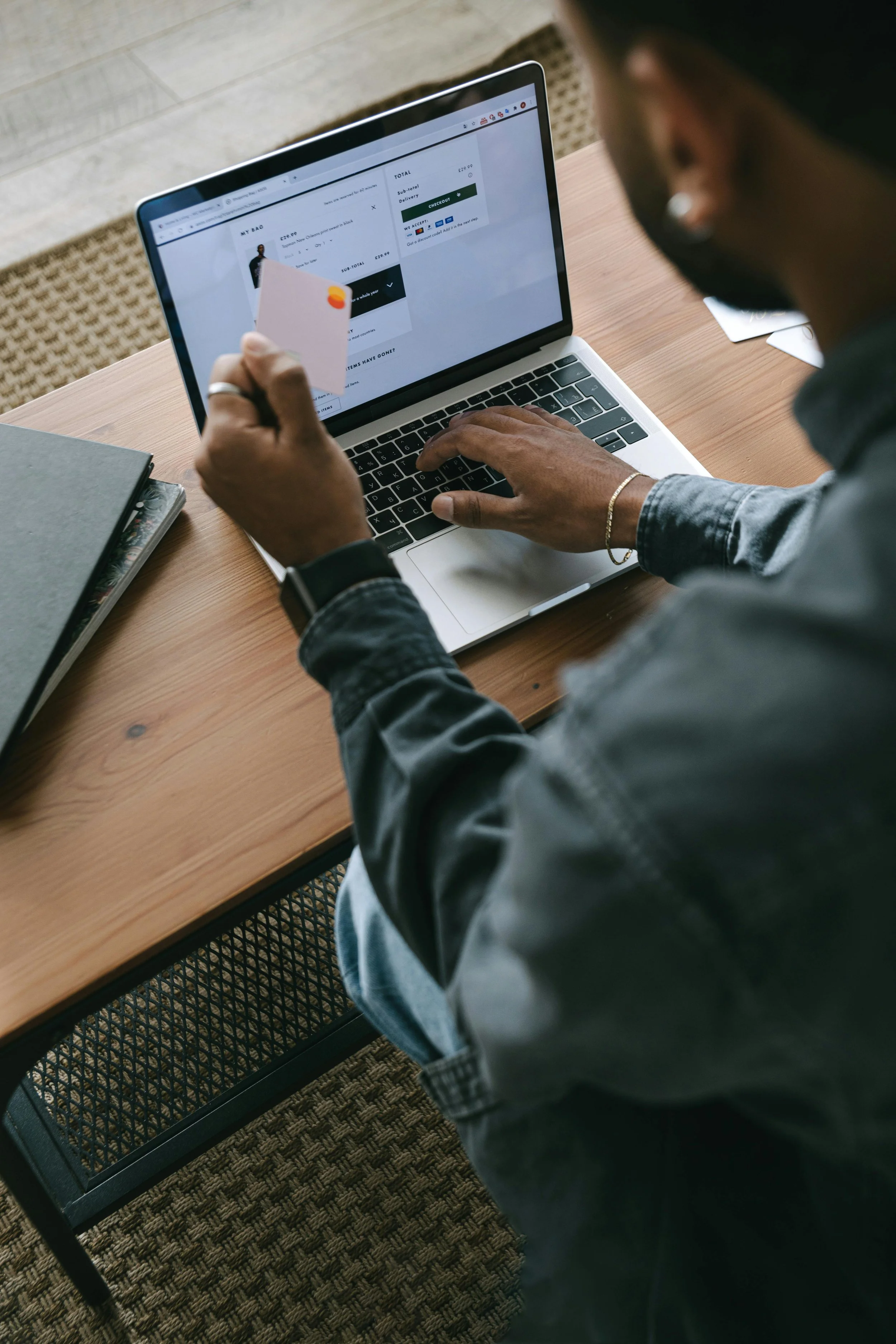 Man shopping online on a laptop, holding a credit card in his left hand.