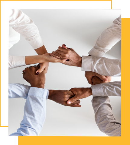 Four people with diverse skin tones stacking their hands together in a gesture of unity.