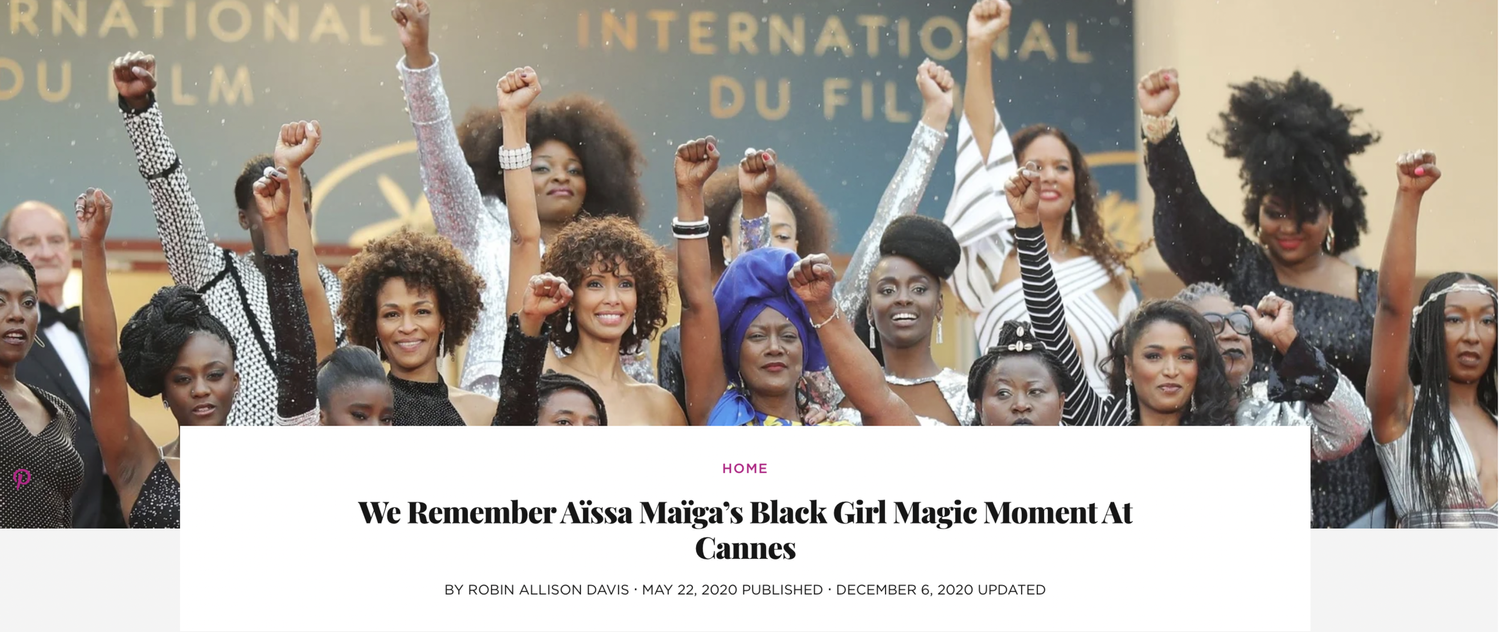Essence Magazine: Group of women celebrating at Cannes film festival, raising fists in solidarity, dressed in glamorous outfits, in front of a backdrop with the Cannes logo.
