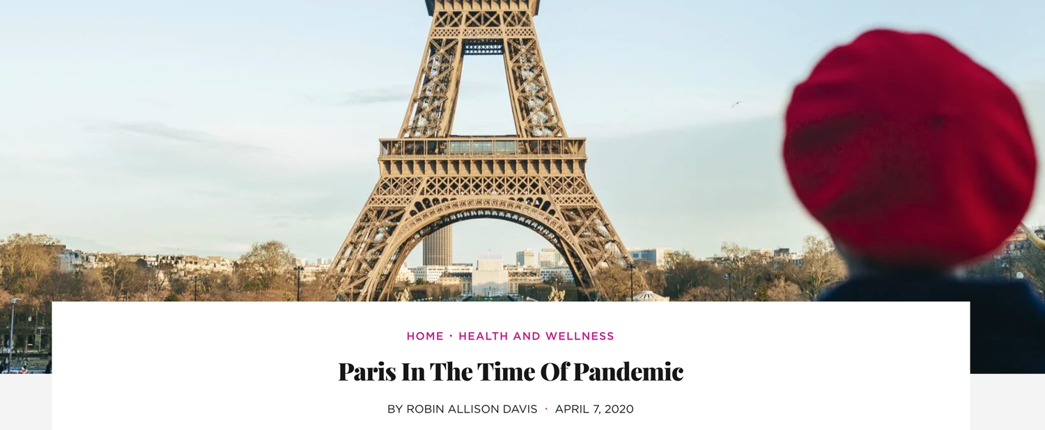 Essence Magazine: A person wearing a red hat looking at the Eiffel Tower in Paris, France, with a cityscape and sky in the background.