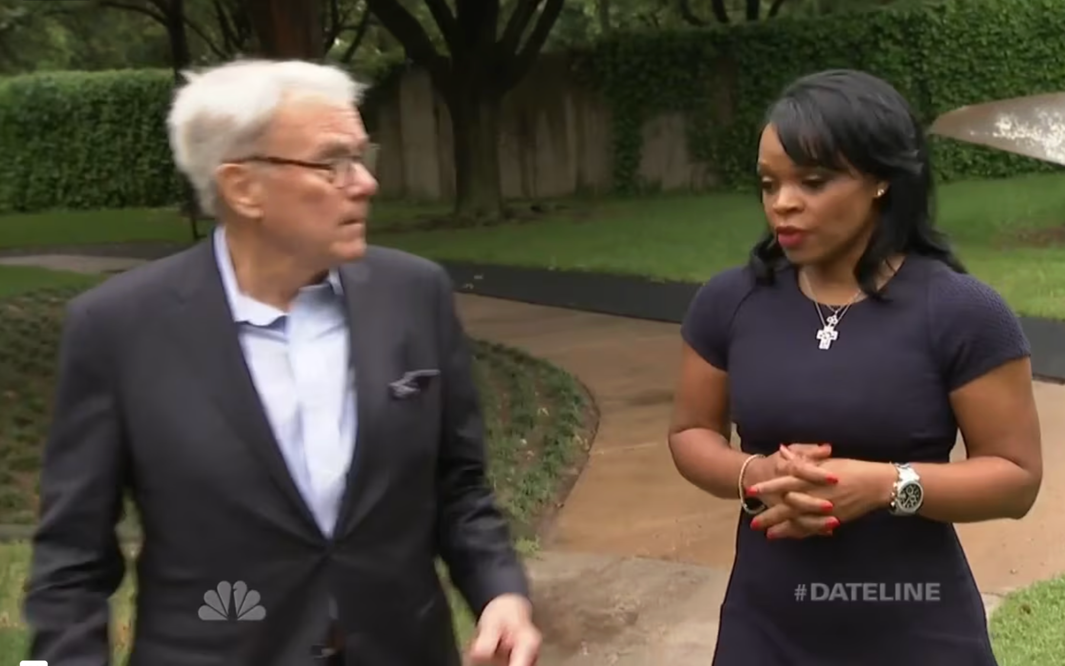 Dateline NBC: Tom Brokaw in a suit and a woman in a black dress having a conversation outdoors on a sidewalk, with trees and bushes in the background.