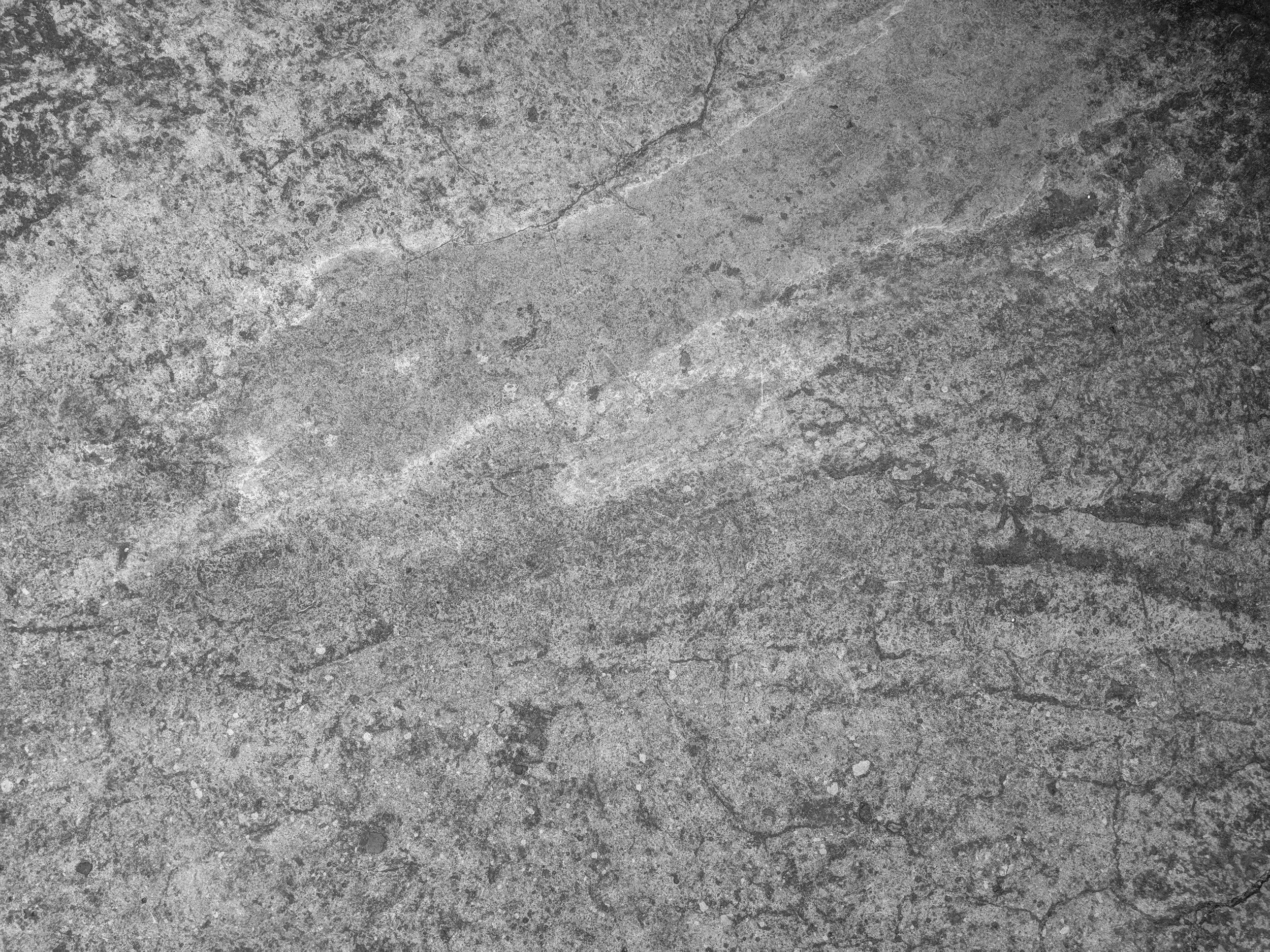 Close-up of a rough grey concrete surface with visible cracks and texture.
