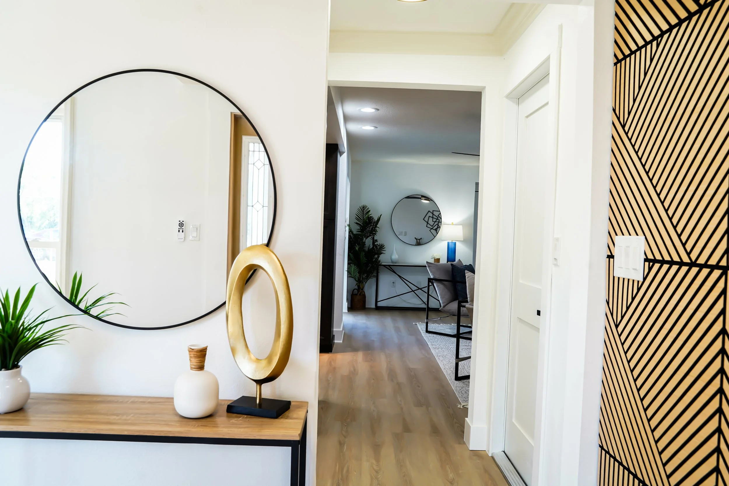 Interior of a modern home with decorative mirrors, vases, plants, and stylish furniture.