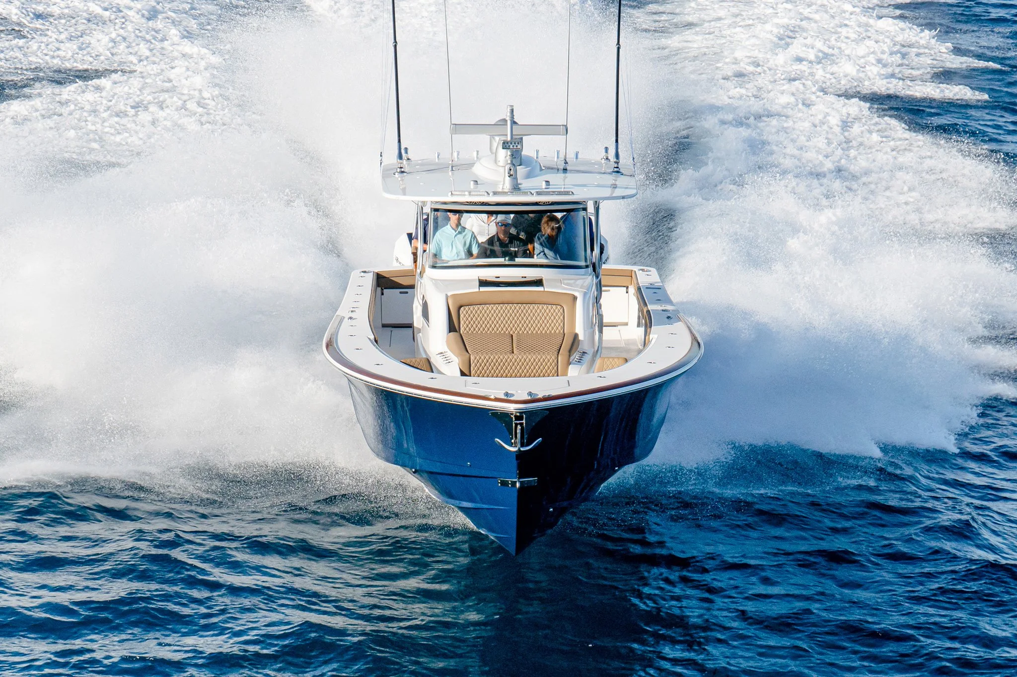 A yacht speeding on the water with a wake behind it, three people inside the yacht visible through the window.