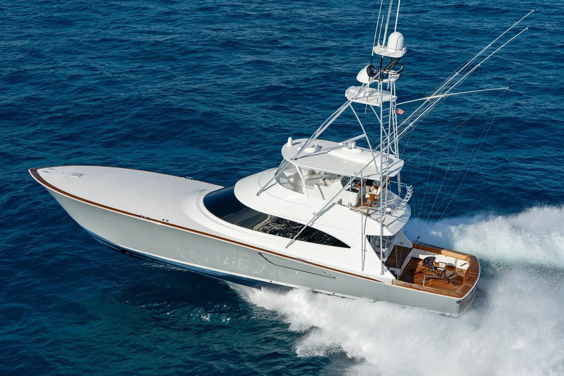 A white yacht sailing in the ocean with a wake behind it, featuring multiple decks, antennas, and a small American flag.