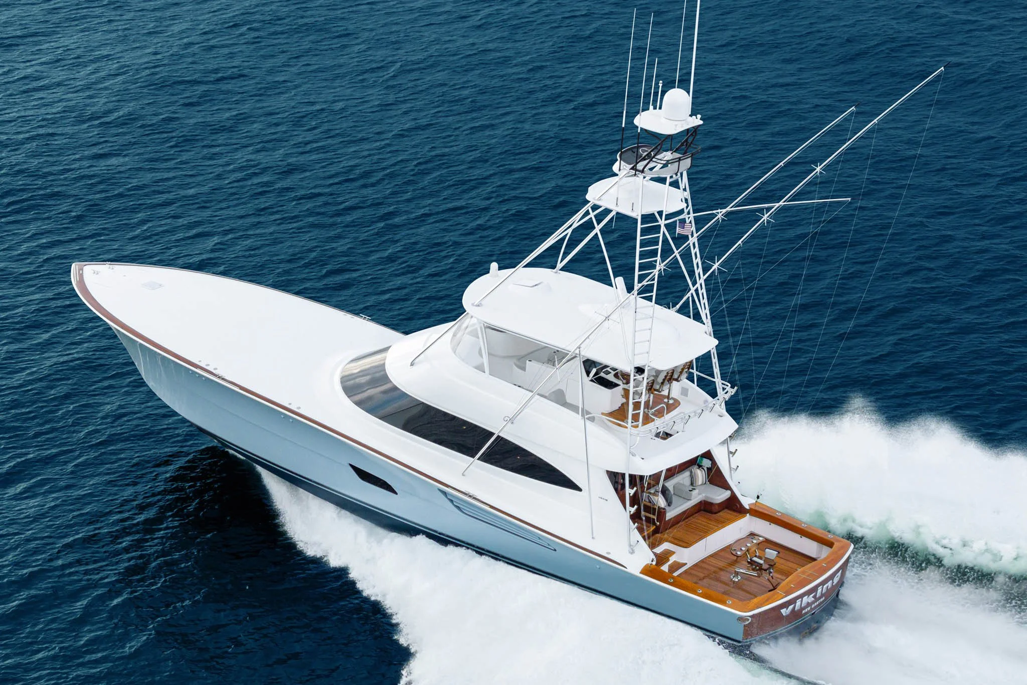 A white yacht speeding through the ocean, creating waves behind it.