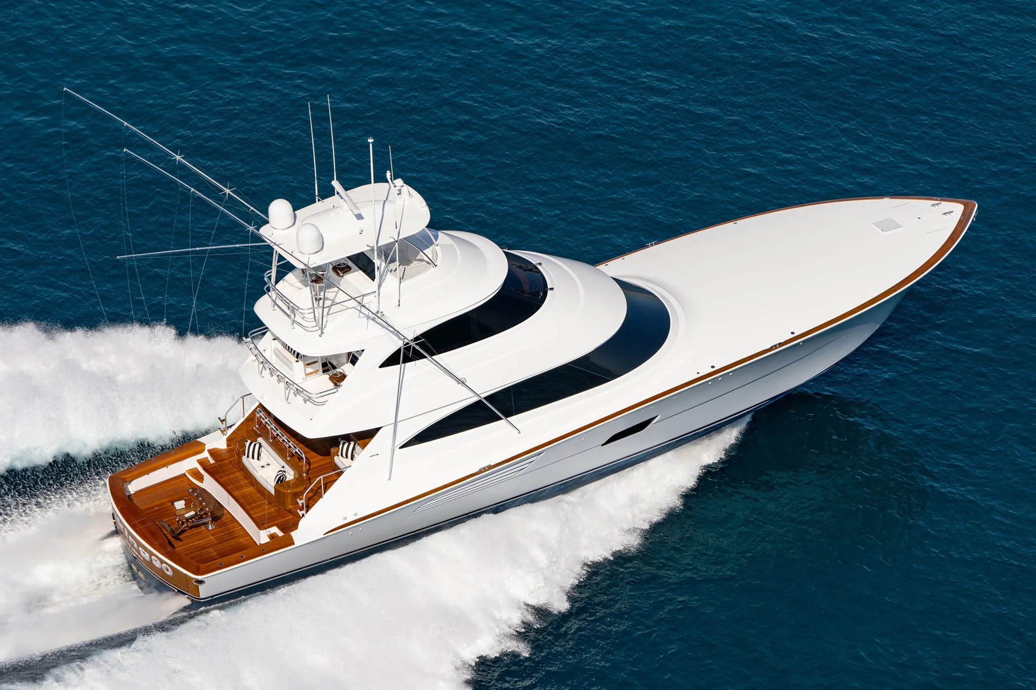 A white luxury yacht sailing in open blue water, with visible deck and upper helipad area.
