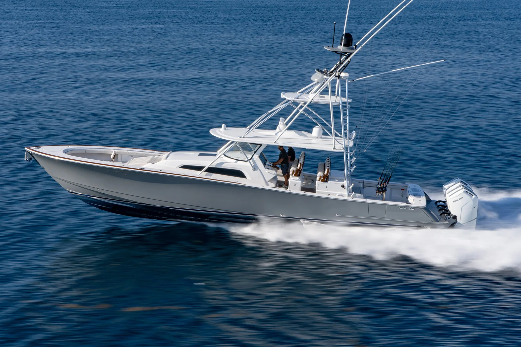 A speedboat sailing on the ocean with a person on board steering the boat.