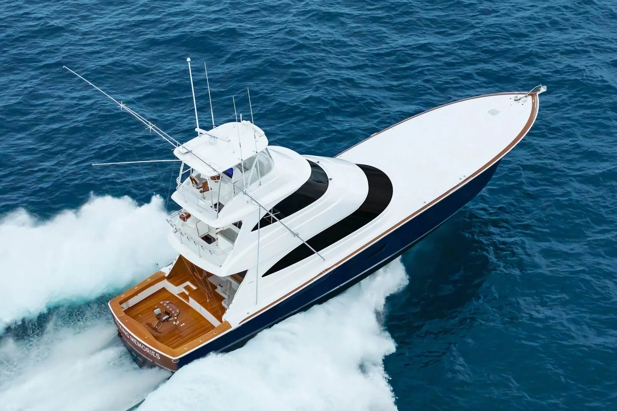 A large white luxury yacht cruising on the ocean, creating a wake behind it.