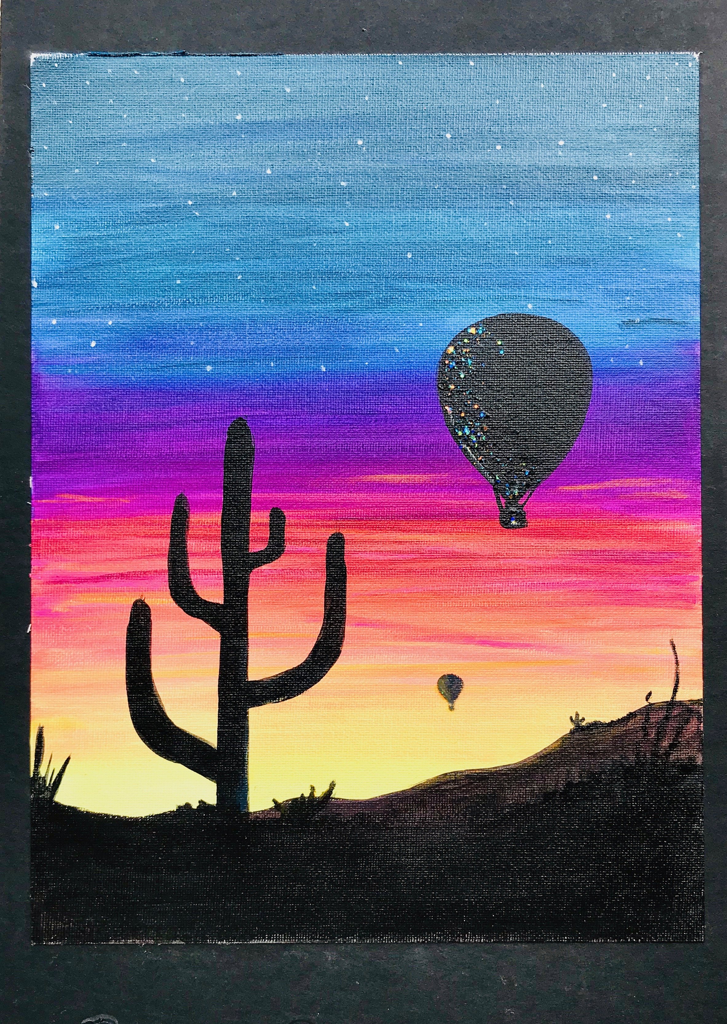 A colorful sunset or sunrise sky with stars, silhouette of a cactus, and hot air balloons in the sky.