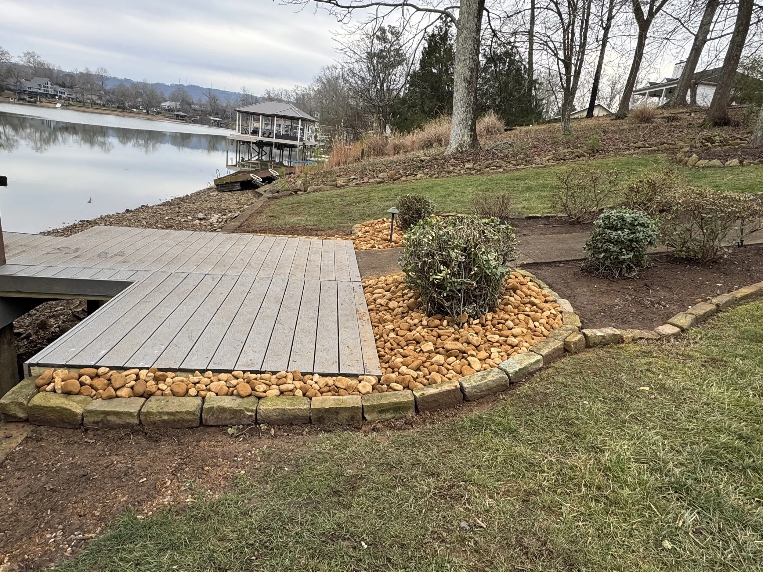 Waterfront deck area with landscaped stone borders creating a peaceful outdoor retreat.
