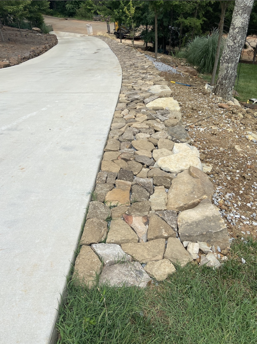 Concrete sidewalk paired with decorative rock drainage for durability and visual contrast.
