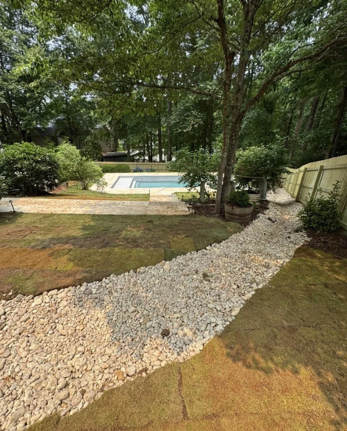 Gravel garden pathway curving naturally through the landscape toward a backyard pool area.