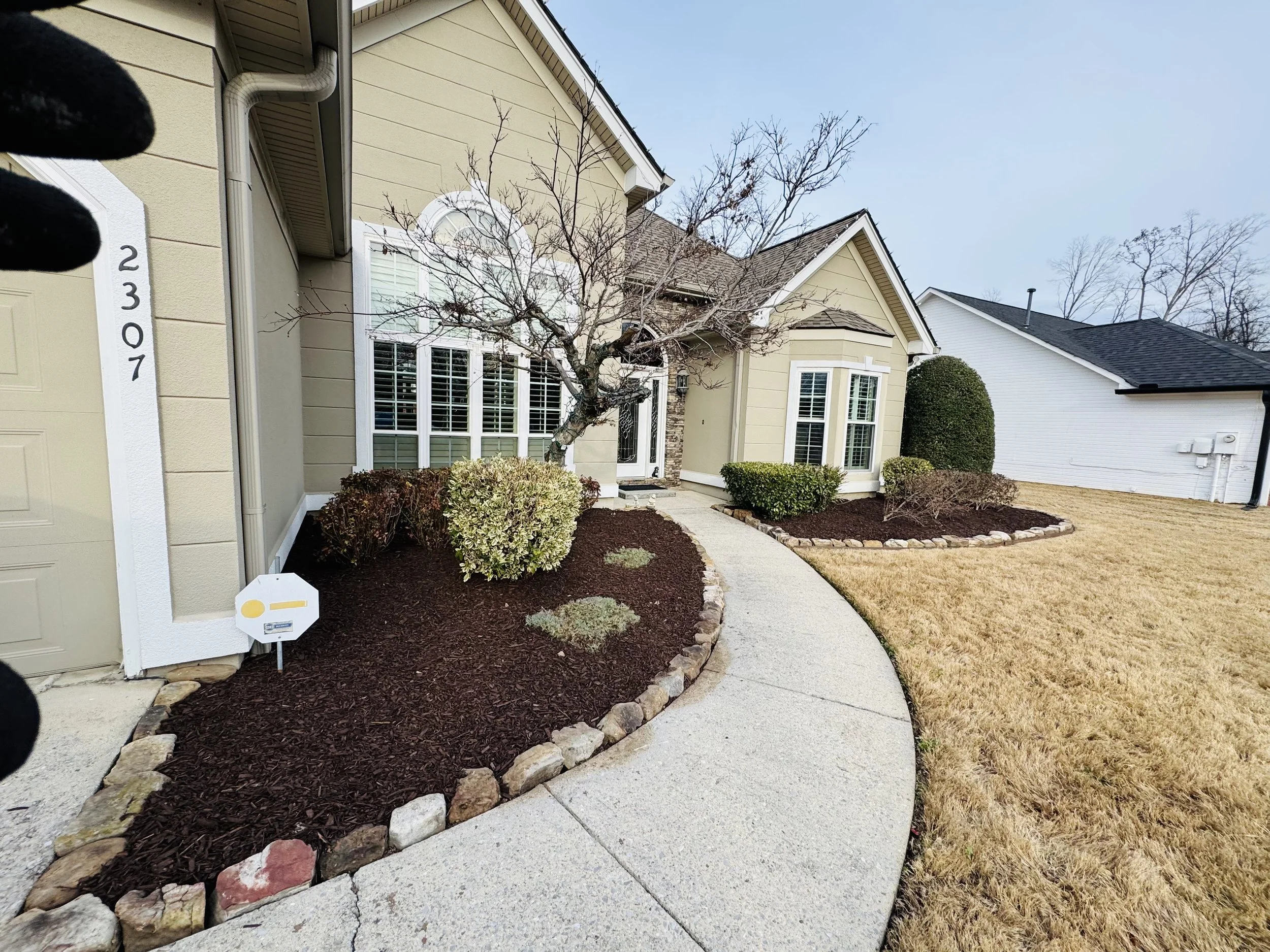 Curved front walkway with stone borders and mulch beds for a clean, elegant entrance.