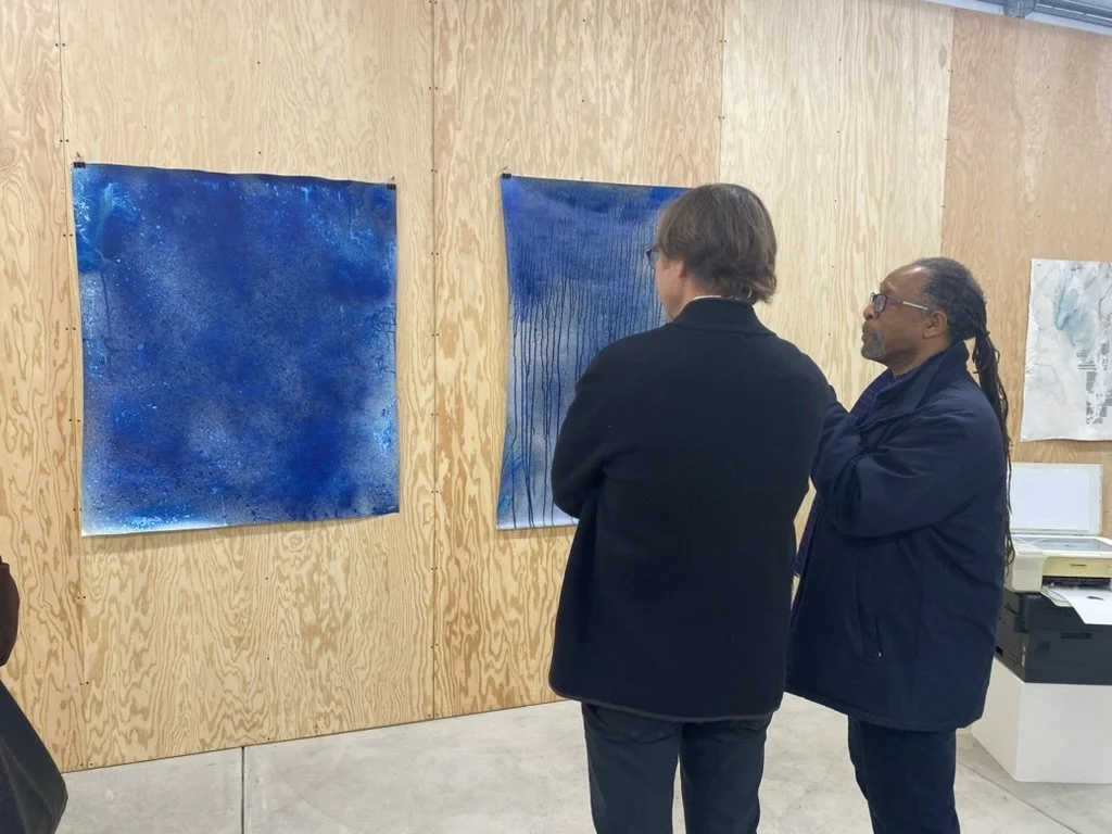 Two people look at artwork on the wall
