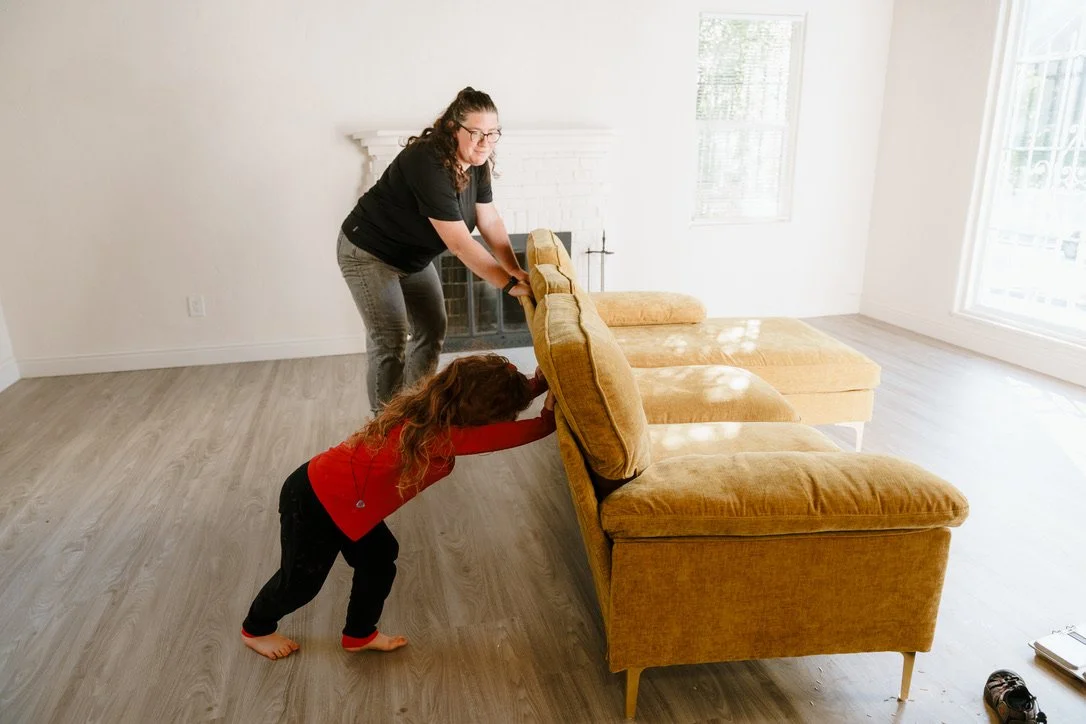 Woman and child push a couch in the living room