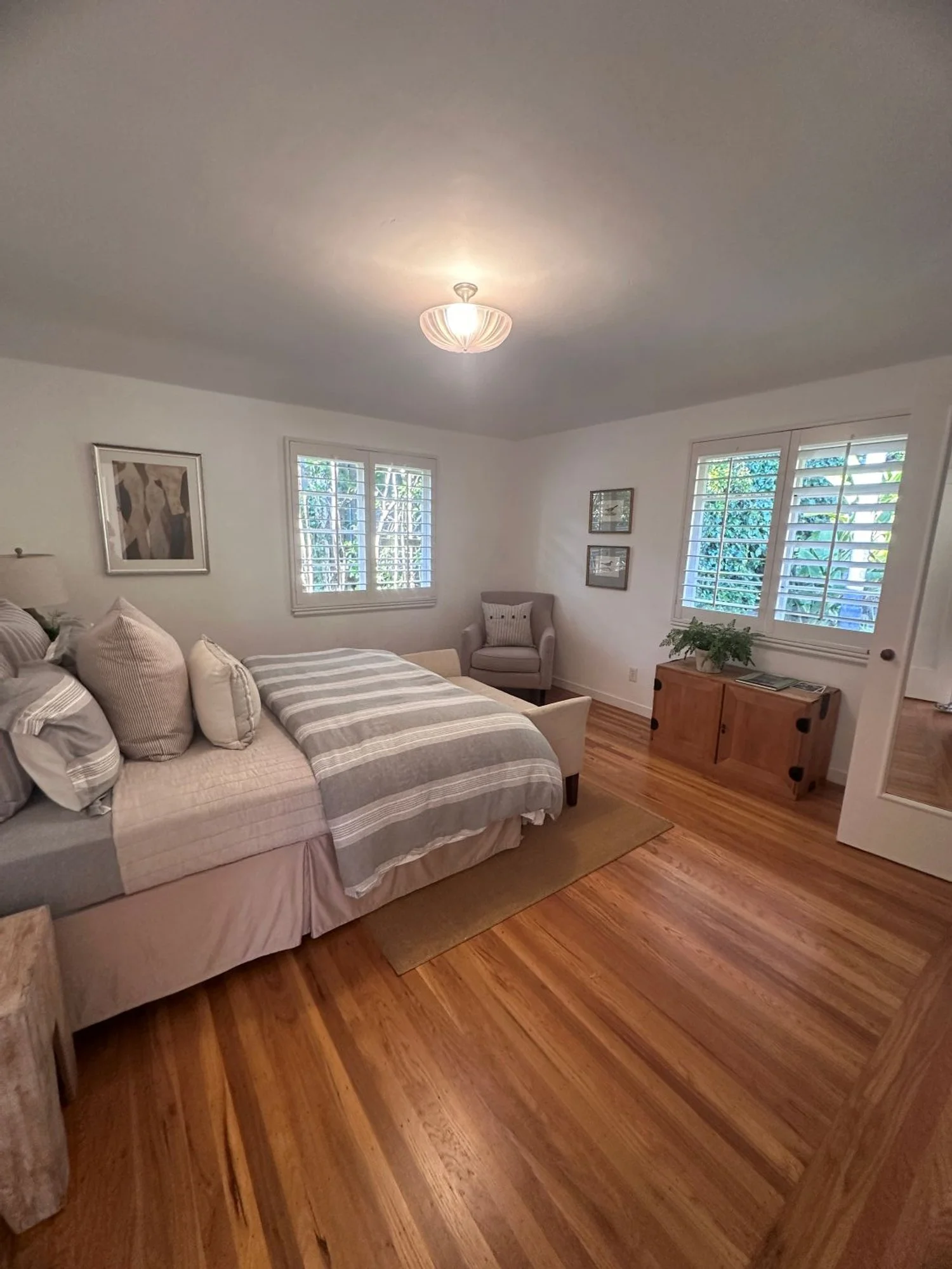 Bedroom with a wood floors, bed, and two windows