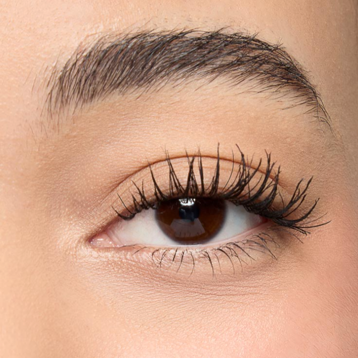 Close-up of a person's eye, showing brown iris, long lashes, well-groomed eyebrow, and smooth skin.