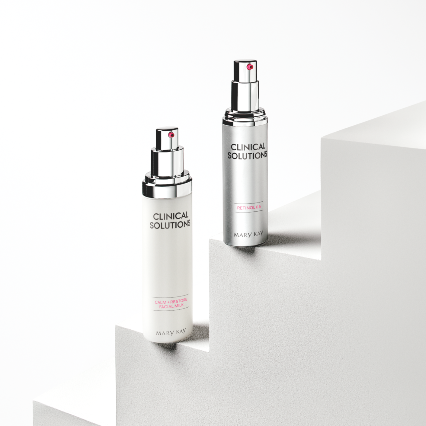 Two Mary Kay Clinical Solutions skincare bottles, one labeled 'Calm + Restore Facial Milk' and the other 'Retinol 0.5', placed on white stepped platforms.