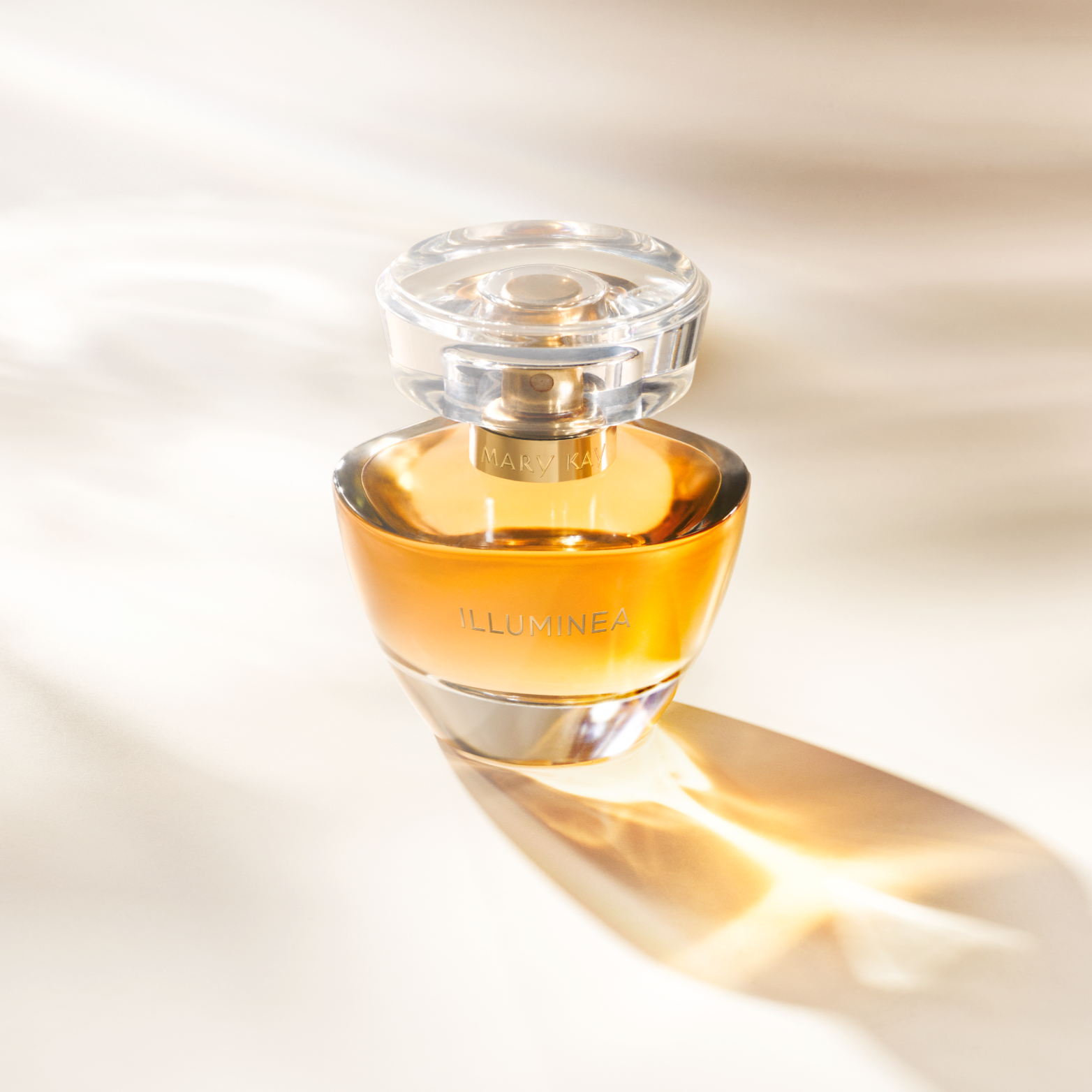 A bottle of Mary Kay Illuminea perfume with a transparent cap, casting a shadow on a light background.
