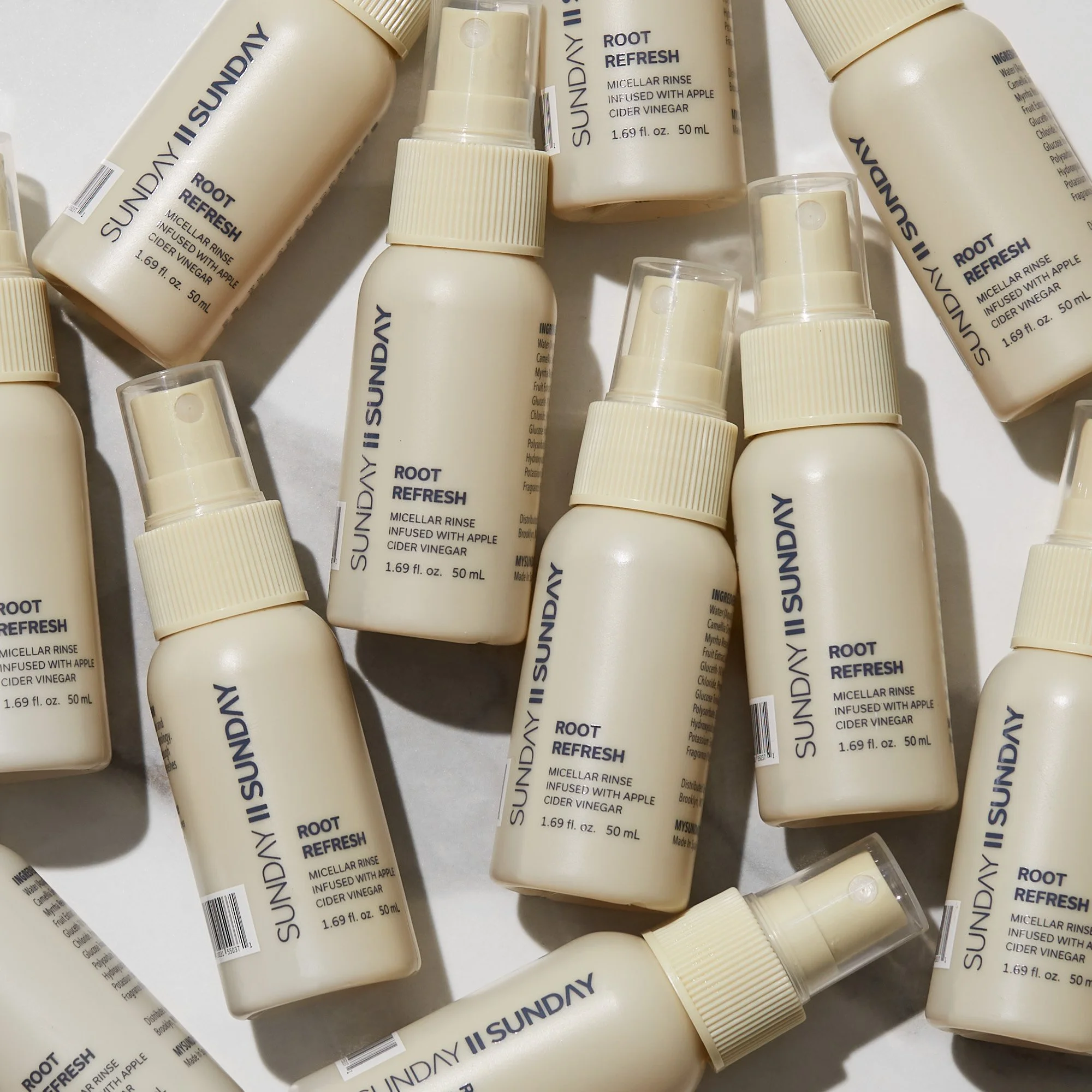 Multiple bottles of SUNDAY II ROOT REFRESH Micellar Rinse infused with apple cider vinegar, arranged on a white surface.