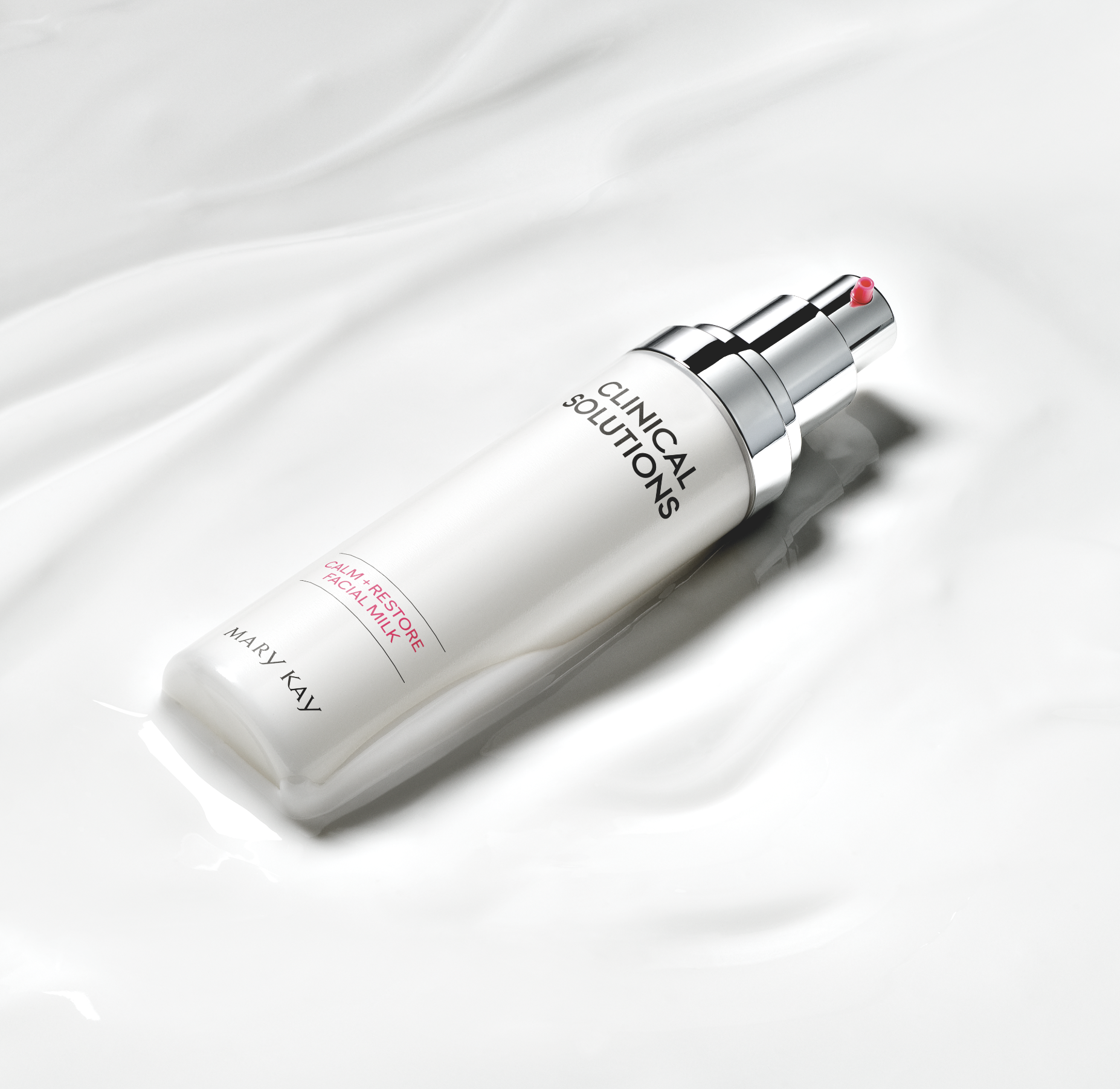 A white bottle of Mary Kay Calm + Restore Facial Milk with a pump dispenser on a white, silky fabric surface.