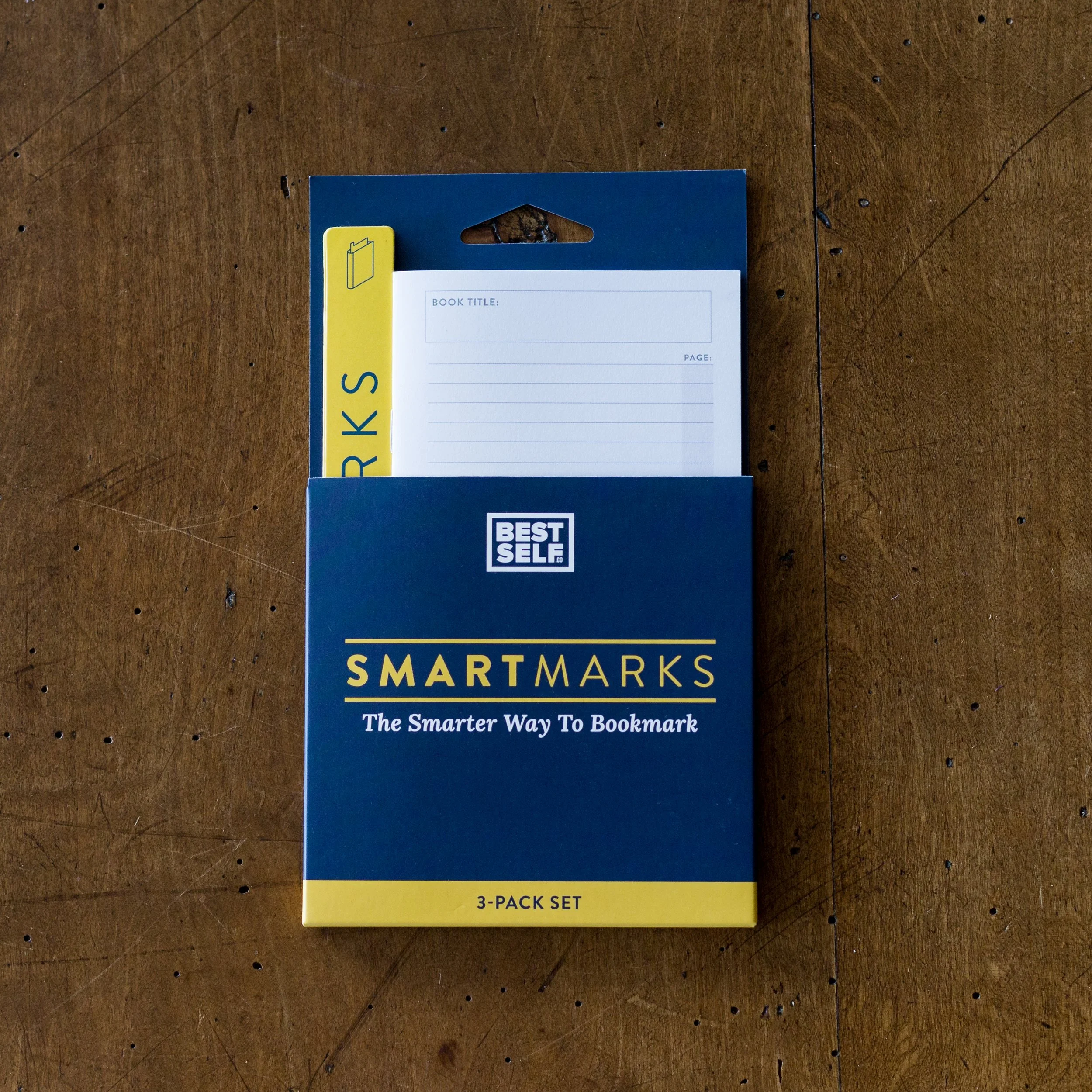 A pack of three Best Self SmartMarks bookmarking notes on a wooden surface