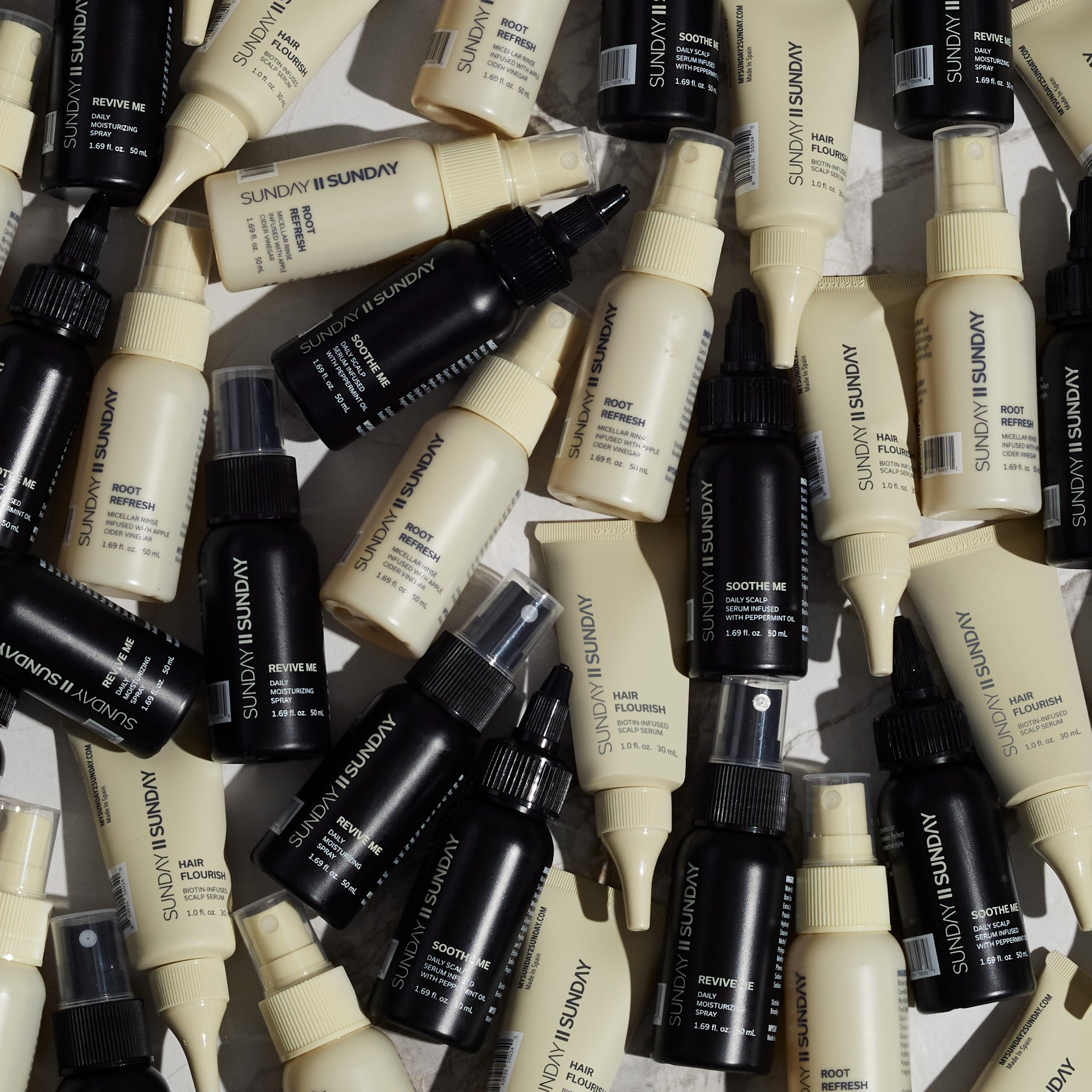 Assorted bottles of SUNDAY skincare products, including sprays, serums, and creams, arranged on a flat surface.