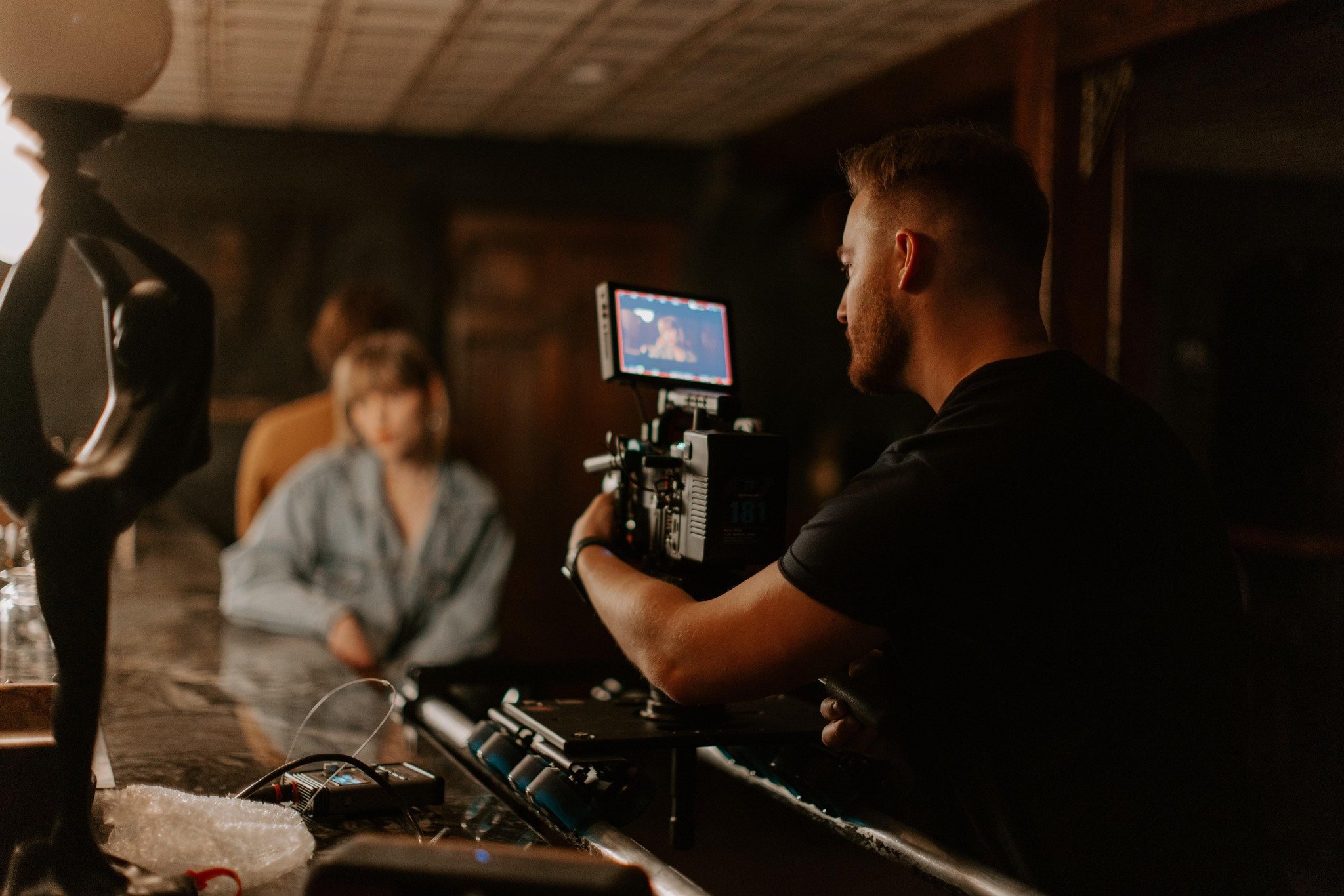 A person filming a woman sitting at a bar with a camera on a stabilizer.