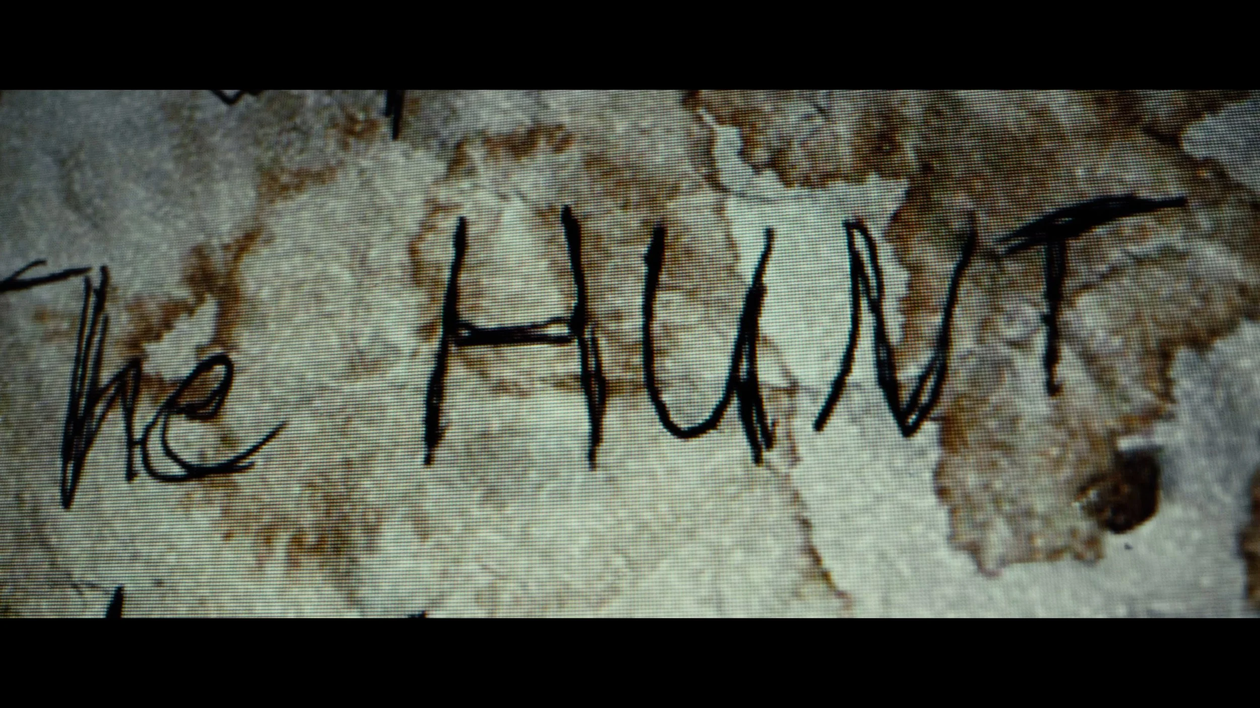 A handwritten note with the words "The Hunt" written in black ink on an old, torn piece of paper.