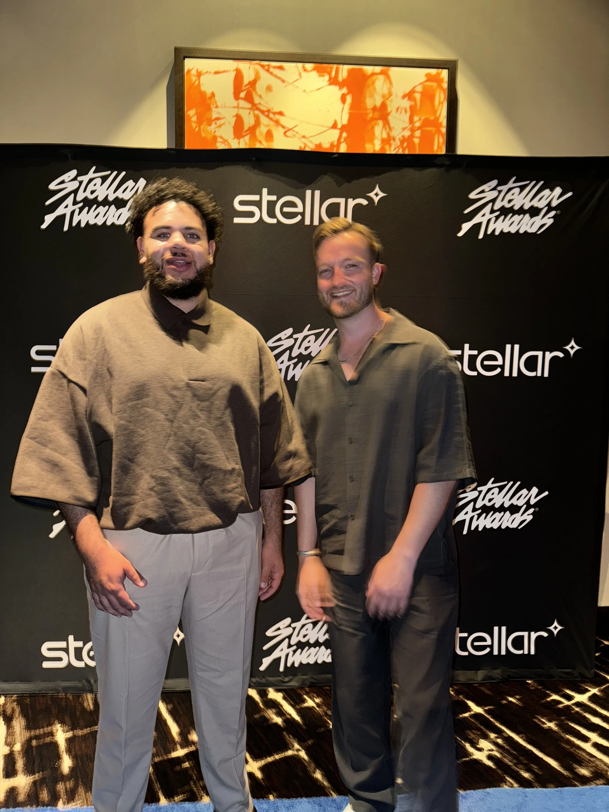 Two men standing in front of a backdrop with 'Stellar Awards' and 'Stellar' logos, posing for a photo at an award event.